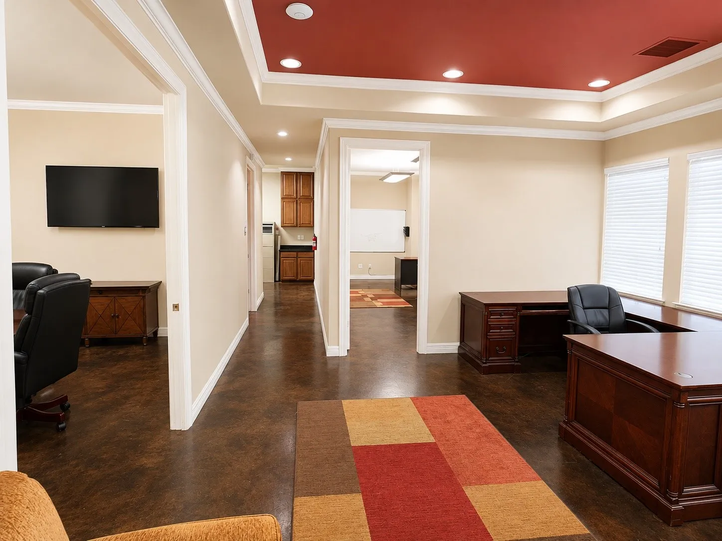 Spacious interior featuring a distinctive tray ceiling with recessed lighting, dark wood-finish flooring, and multiple open doorways