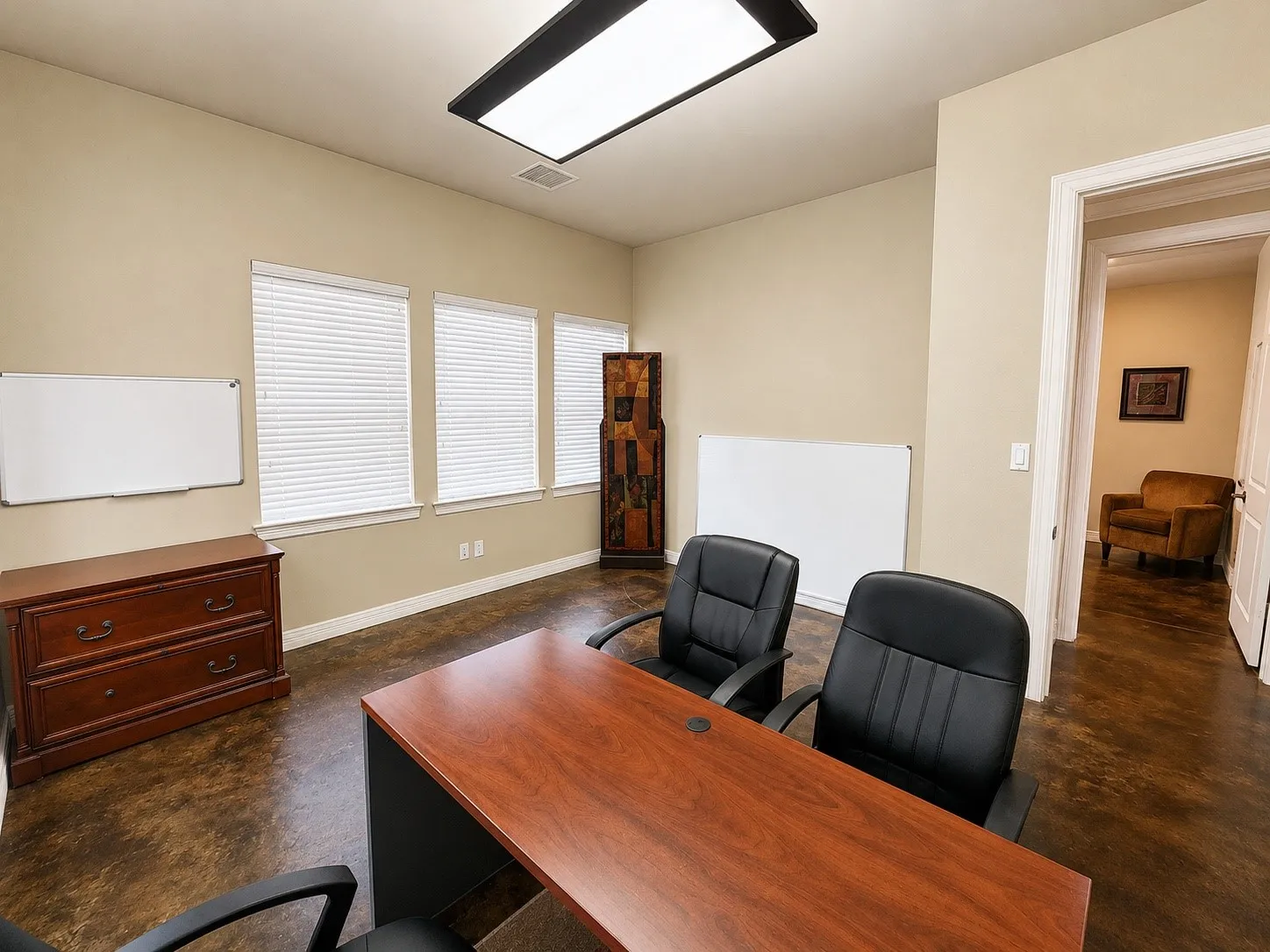 Spacious room featuring three windows with blinds, recessed ceiling lighting, a neutral wall color, and rich, dark-toned flooring