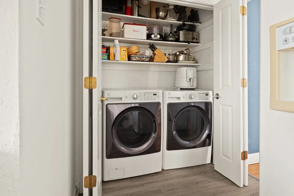Dedicated laundry closet featuring a stacked washer and dryer, integrated shelving, and wood-finish flooring