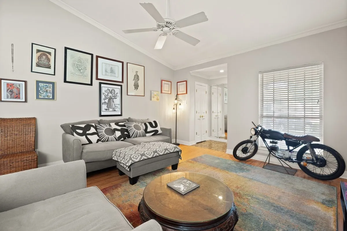 Living area featuring a vaulted ceiling with a ceiling fan, hardwood flooring, and crown molding