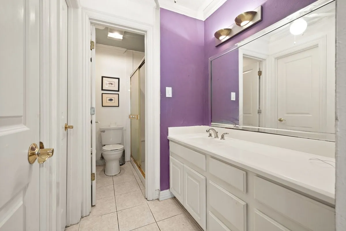 Bathroom featuring a white vanity with integrated sink, a large wall-mounted mirror, and a three-light fixture with shower