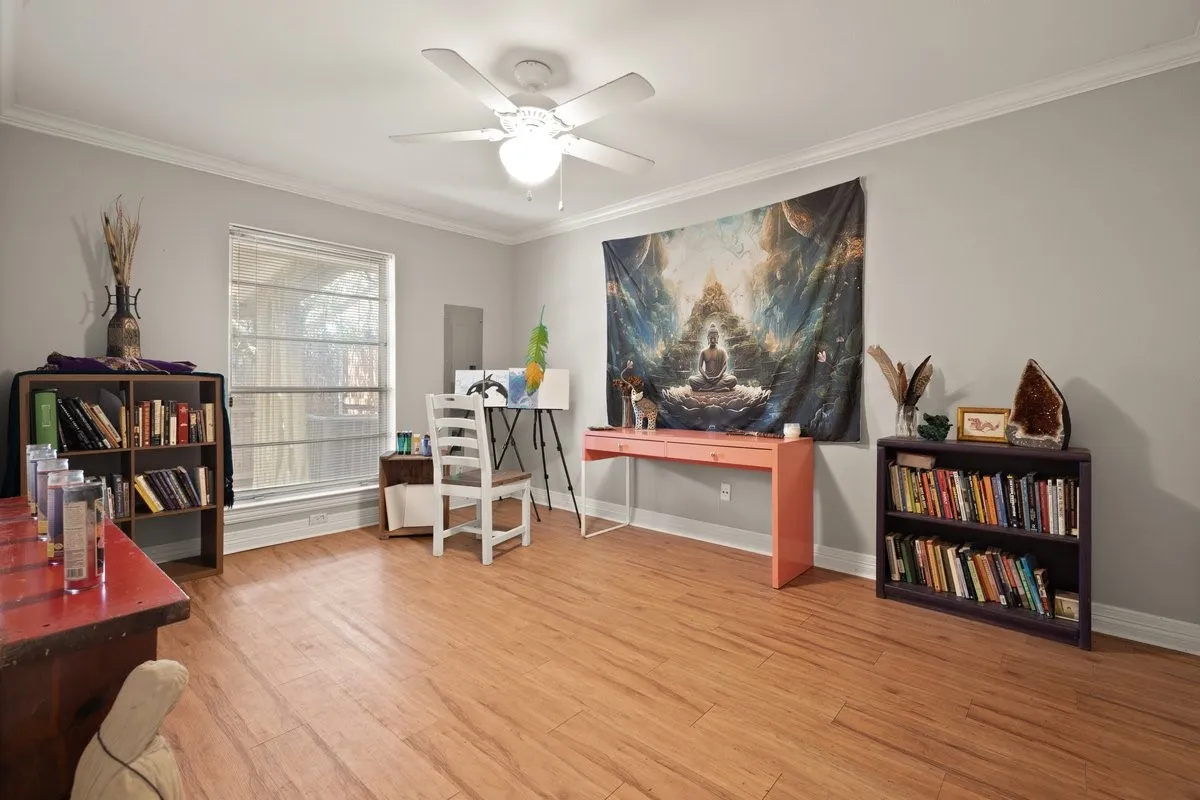 Light laminate wood colored flooring throughout, featuring a ceiling fan with integrated lighting, a large window, and light gray wall paint