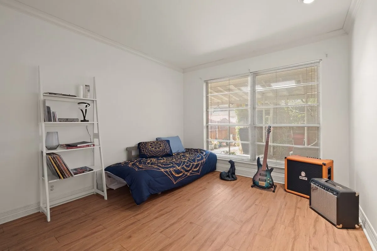 Room featuring laminate flooring, white walls, crown molding, and dual windows with blinds