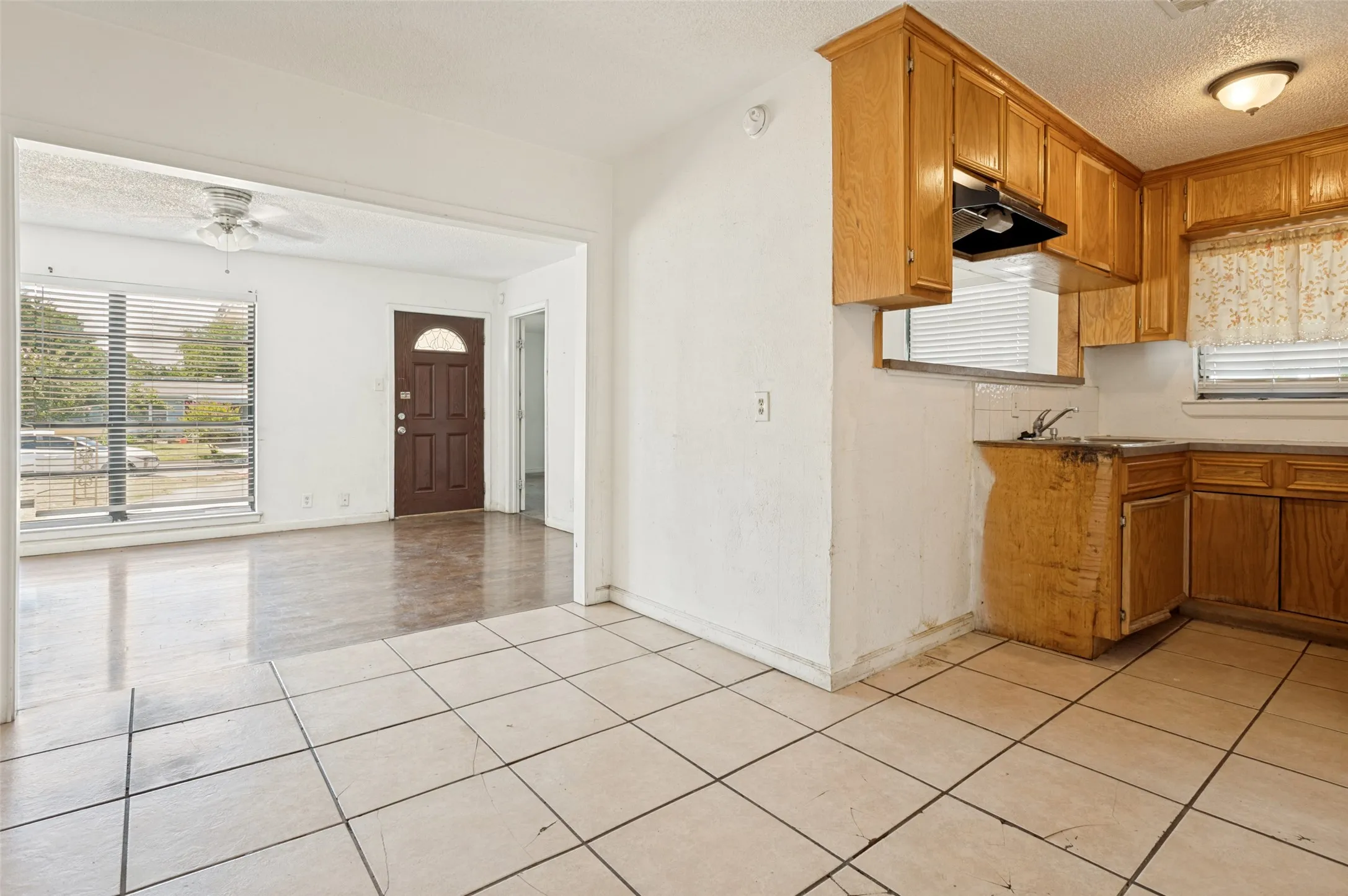 Tile flooring extending into an open living area with wood-finish flooring