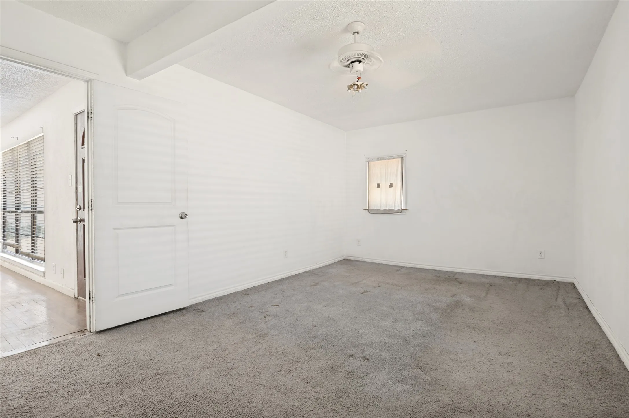 Carpeted room featuring a ceiling fan, a window with blinds, and white walls