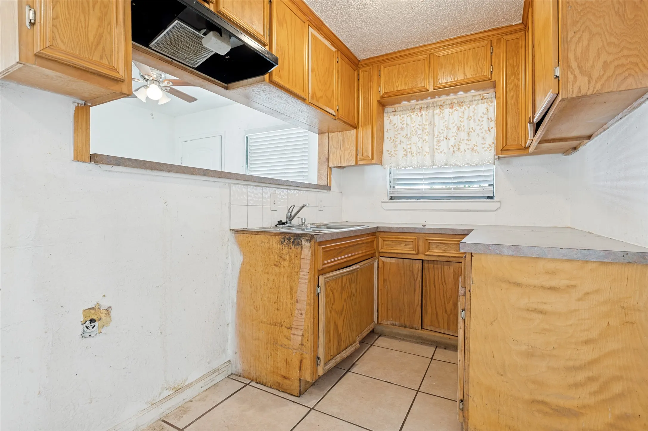 Kitchen featuring wood-finish cabinetry, tile flooring, and a pass-through opening
