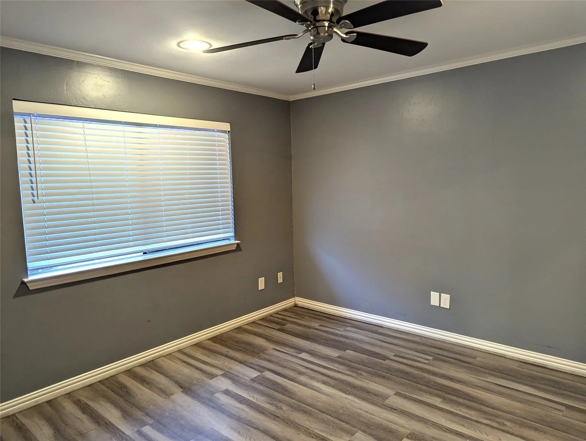 Wood-finish flooring, crown molding, ceiling fan, recessed lighting, and window blinds