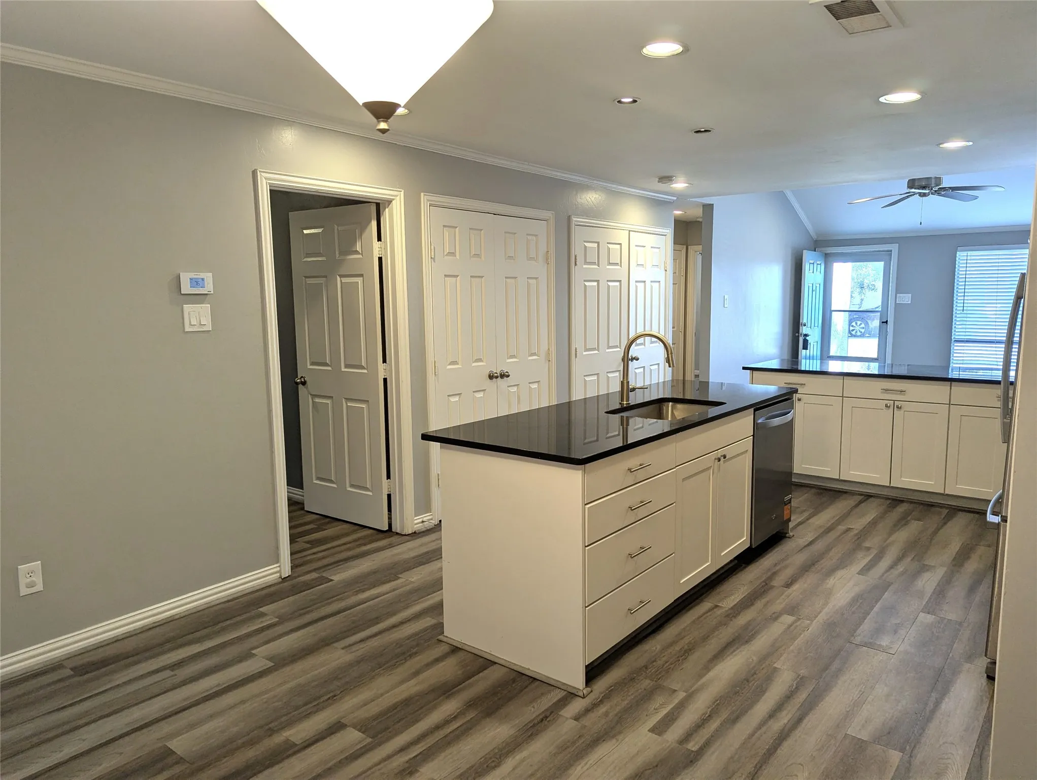 Open-concept kitchen featuring an island with a stainless steel sink and a gooseneck faucet