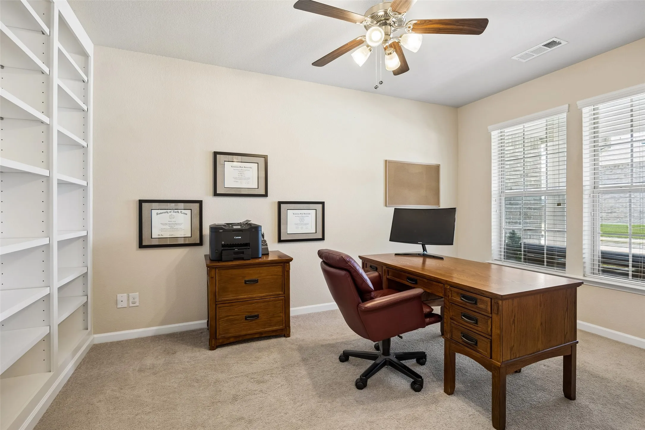 Dedicated home office with extensive built-in shelving and a ceiling fan