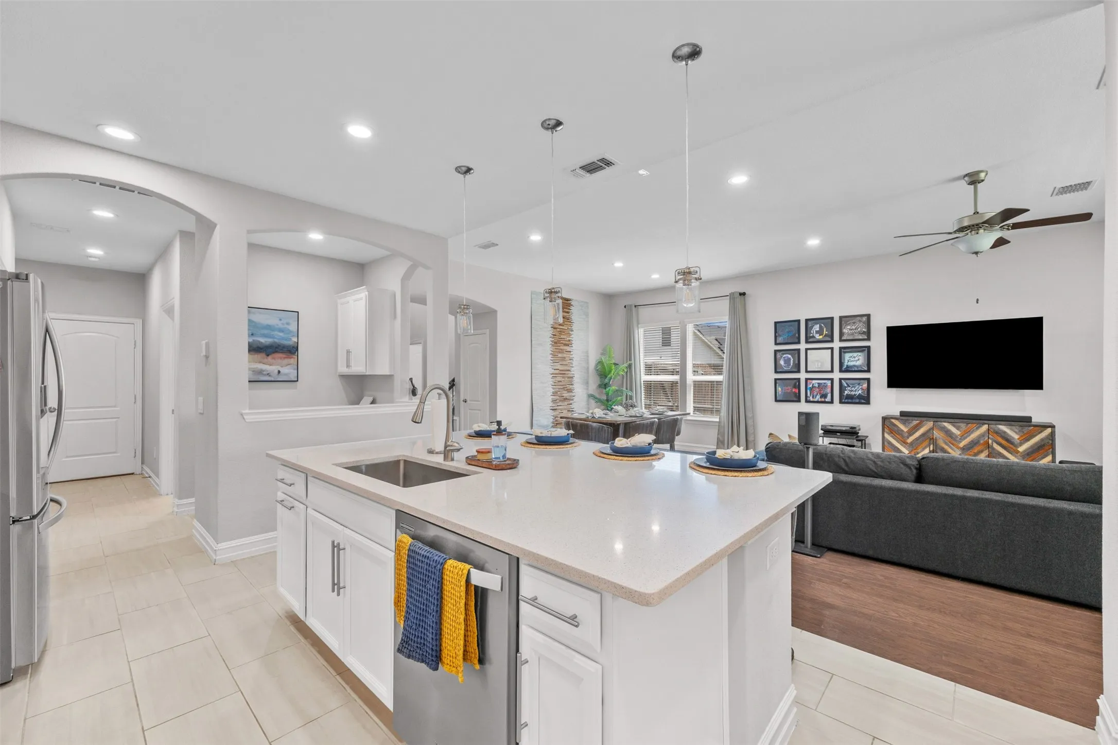 Open concept living space featuring a kitchen island with sink, white cabinetry, and recessed lighting