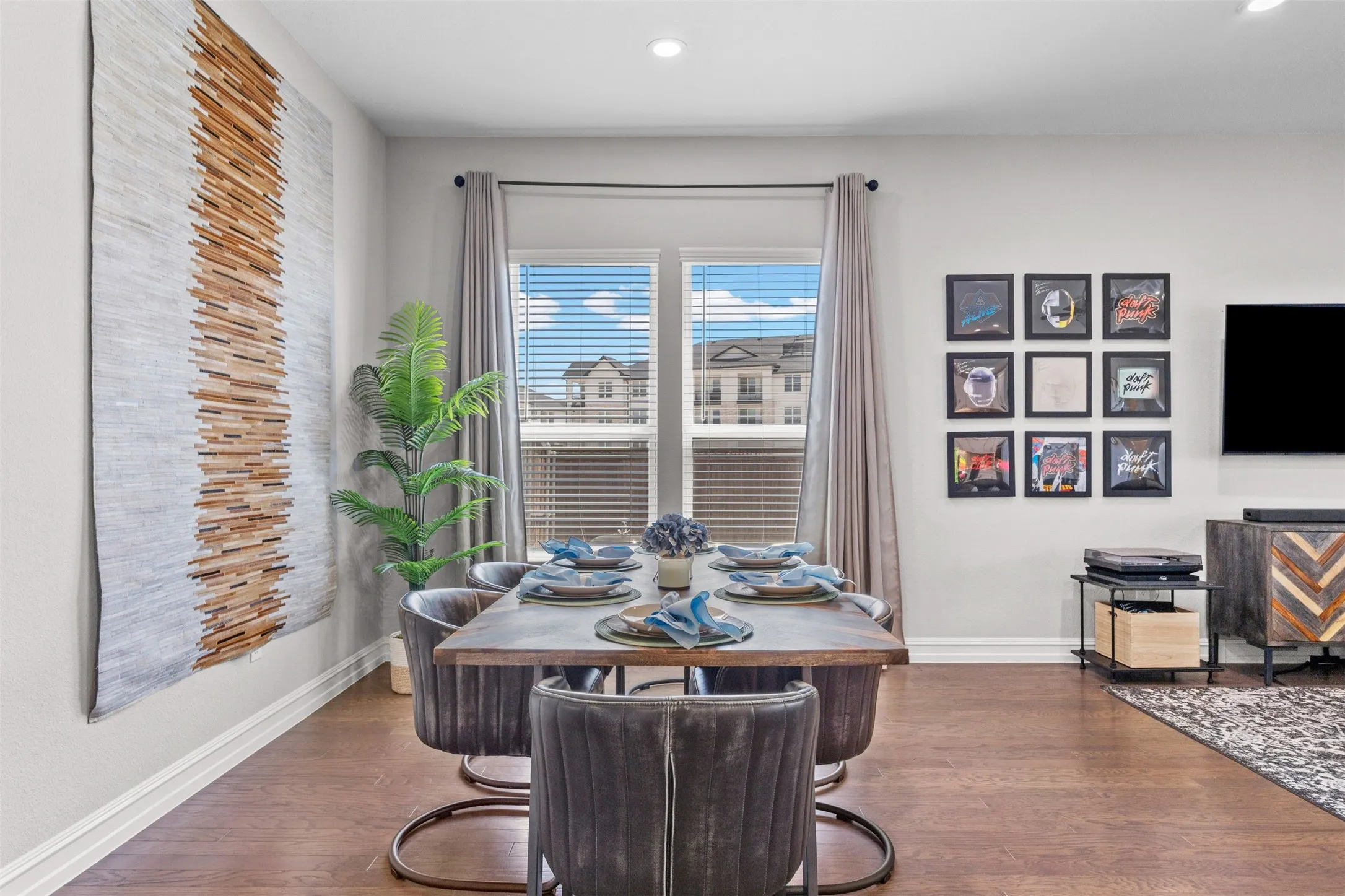 Dining area with wood-finish flooring, white baseboards, and a window with horizontal blinds