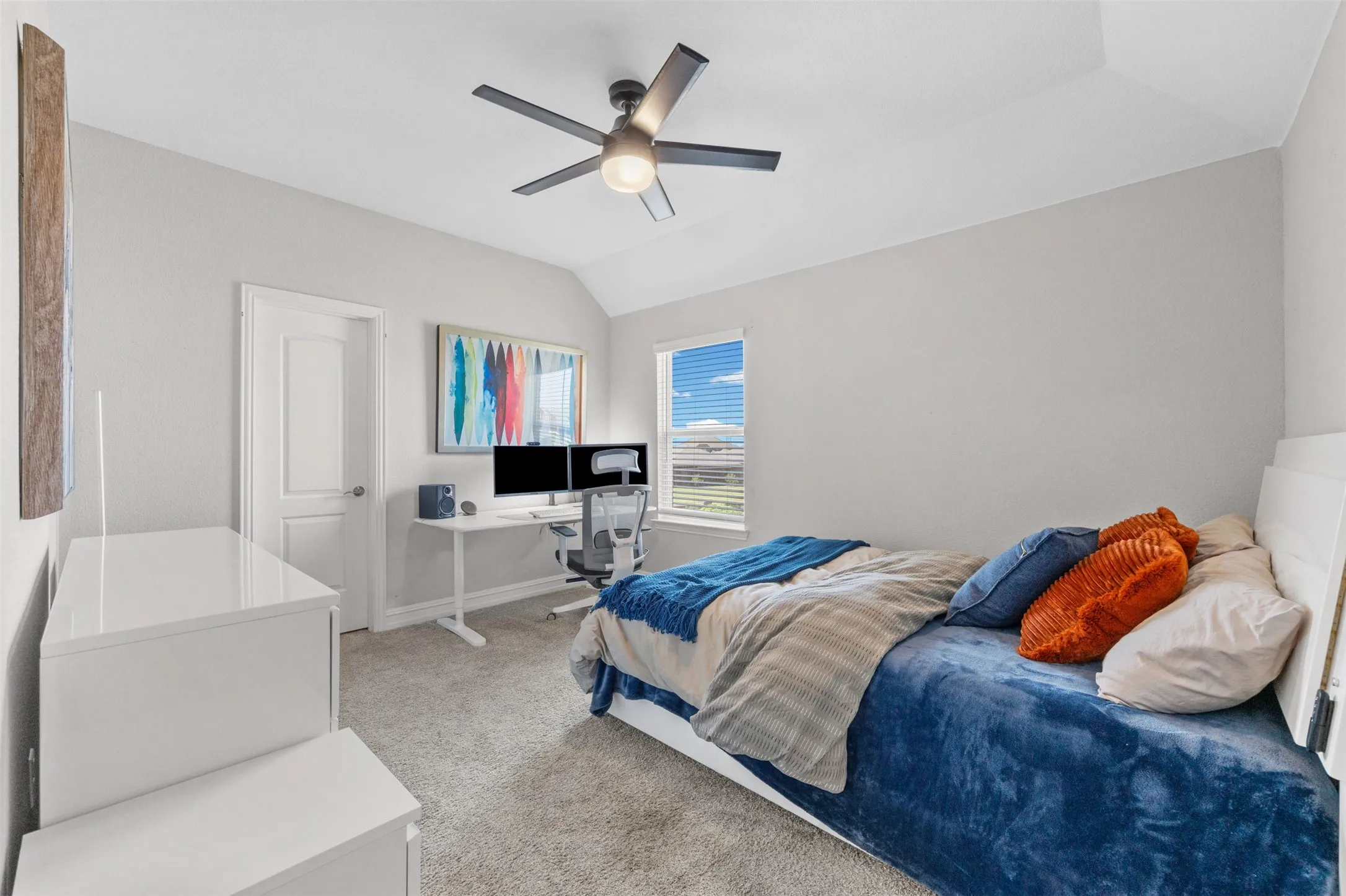 Vaulted ceiling bedroom featuring a ceiling fan with integrated lighting, a large window with blinds, and soft carpet flooring