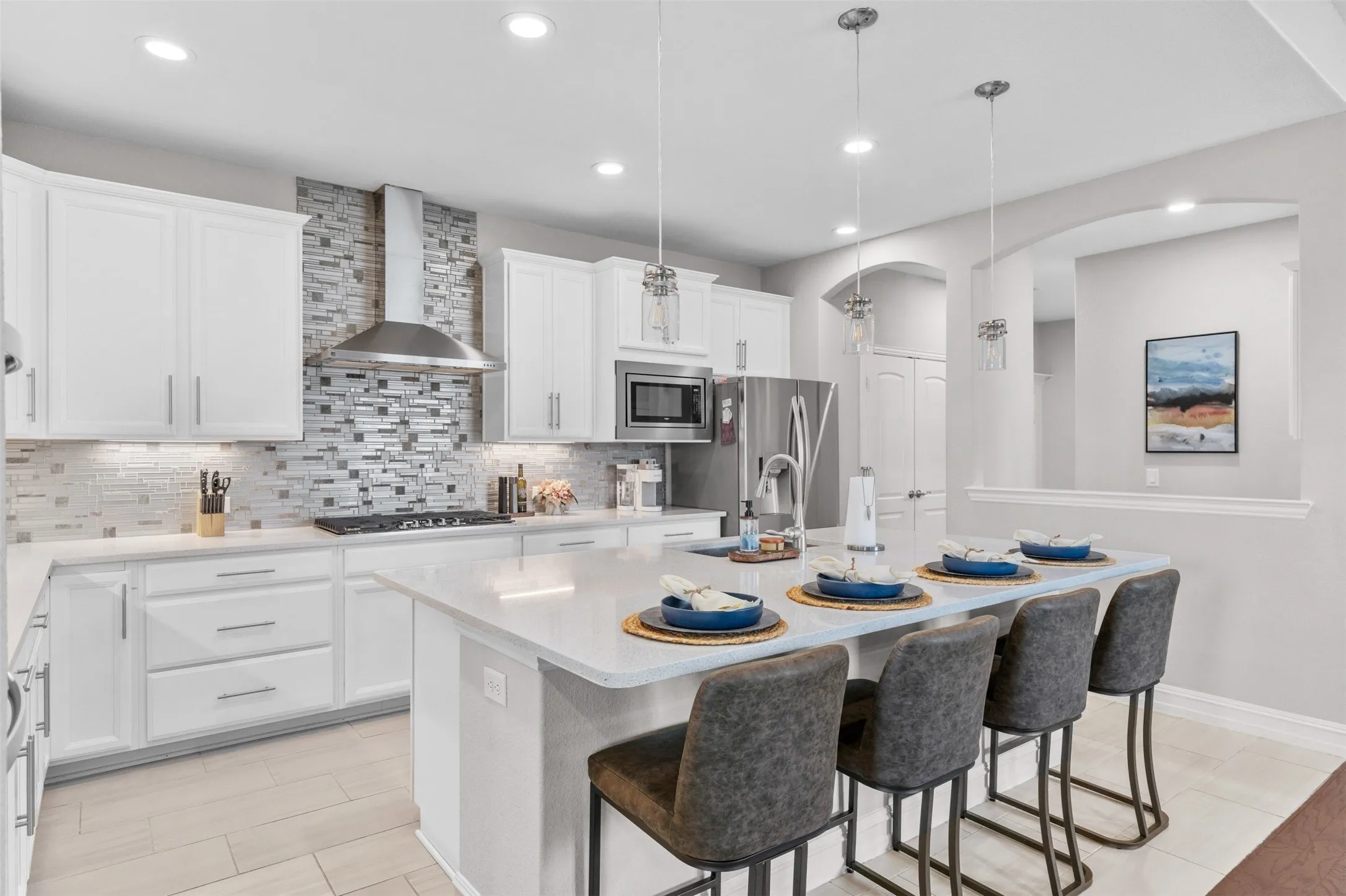 Modern kitchen featuring white cabinetry, a large center island with seating, stainless steel appliances, a tile backsplash, and recessed lighting