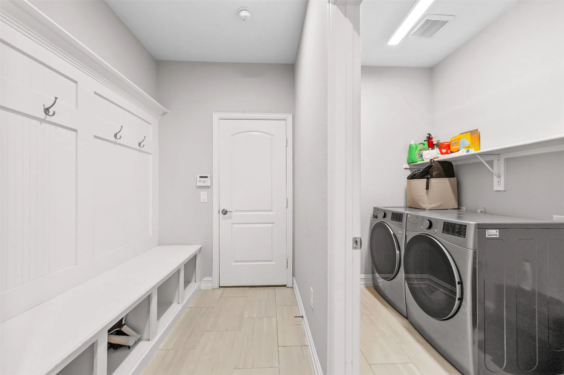 Mudroom featuring built-in bench seating with cubby storage, integrated wall hooks, and light-toned tile flooring