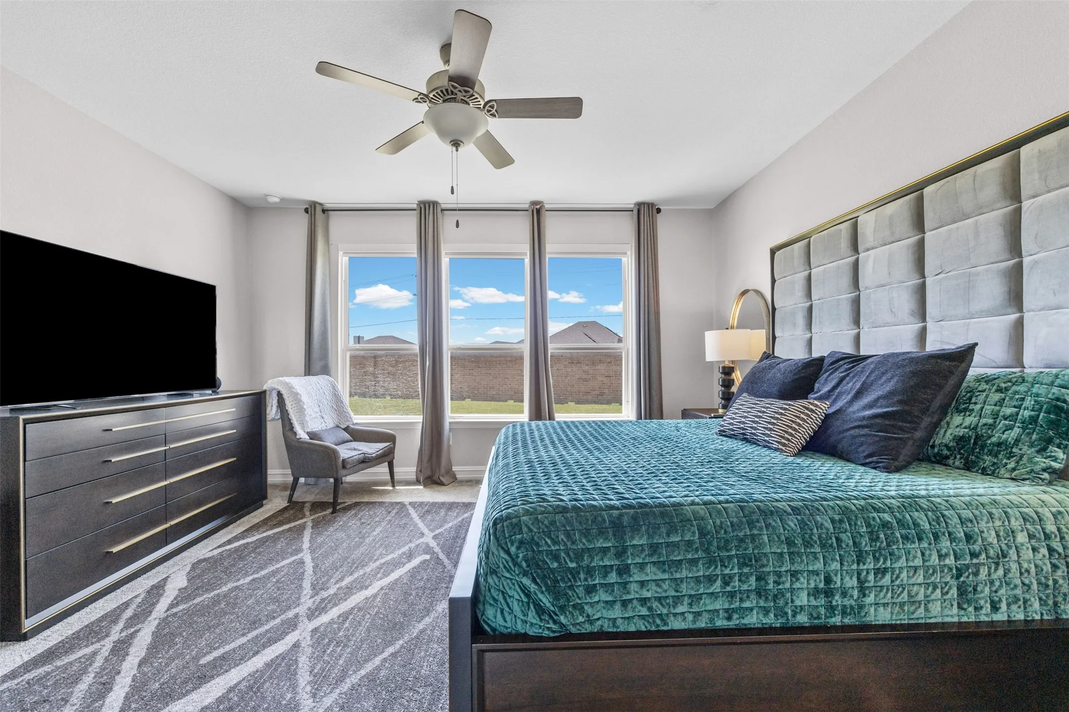 Bright room featuring three windows with exterior views, a ceiling fan, and light-toned walls