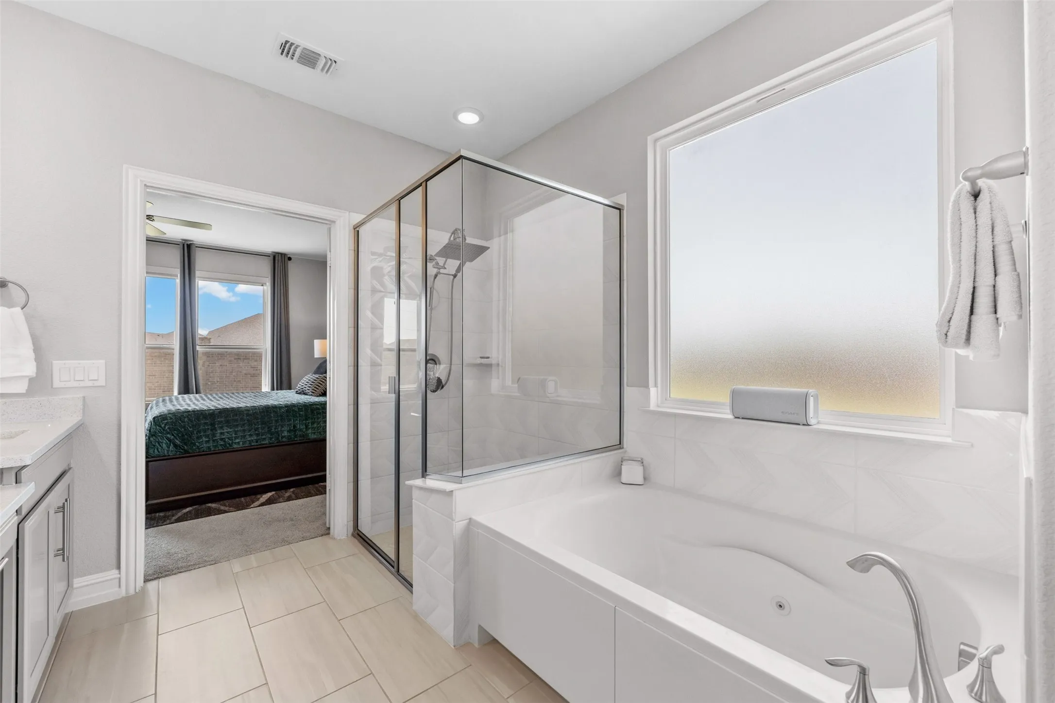 Bathroom featuring a frameless glass shower enclosure, built-in soaking tub, wood-finish tile flooring, recessed lighting, and a frosted window