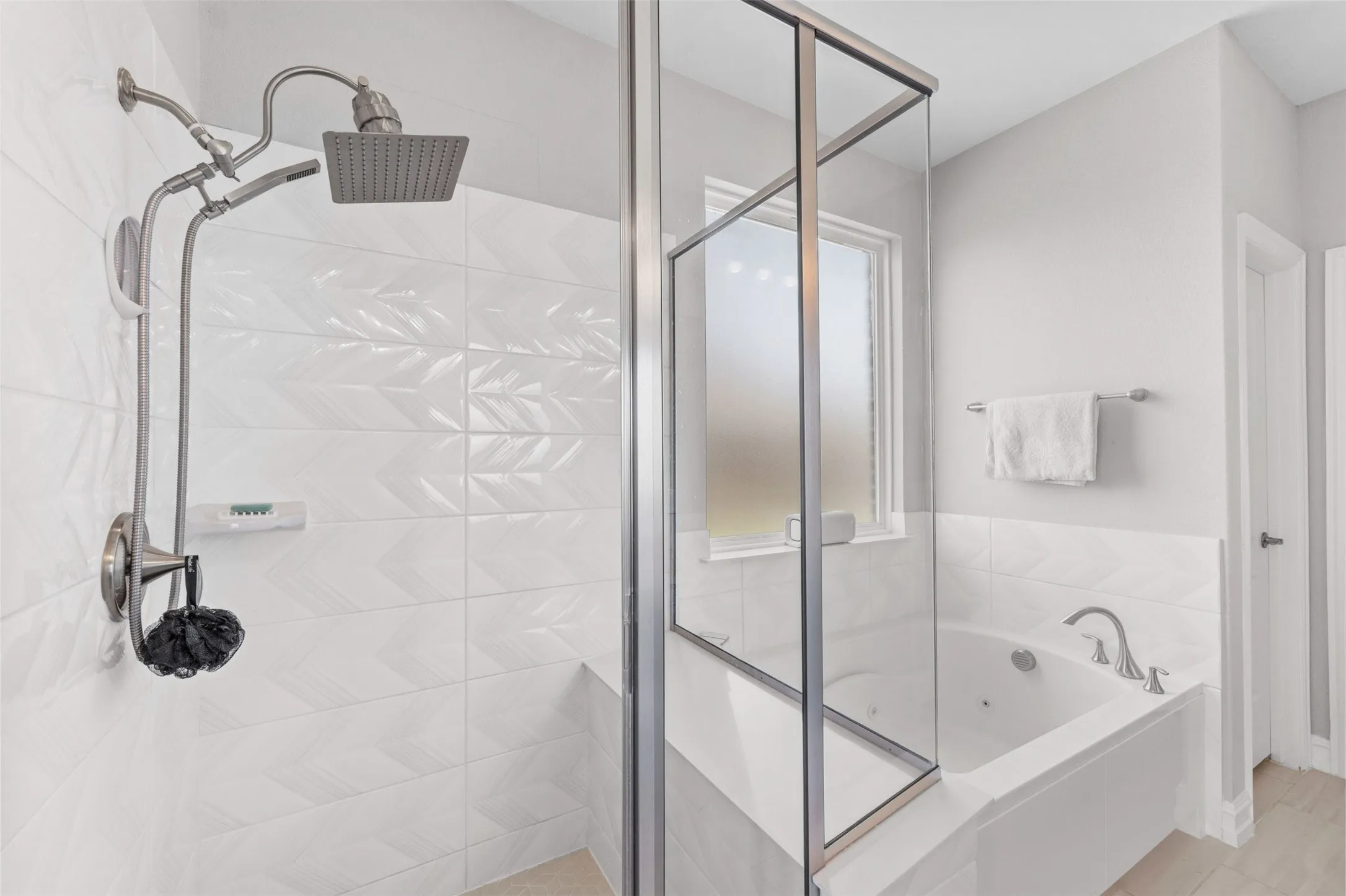 Walk-in shower with a rain showerhead, handheld shower fixture, and textured white tile surround