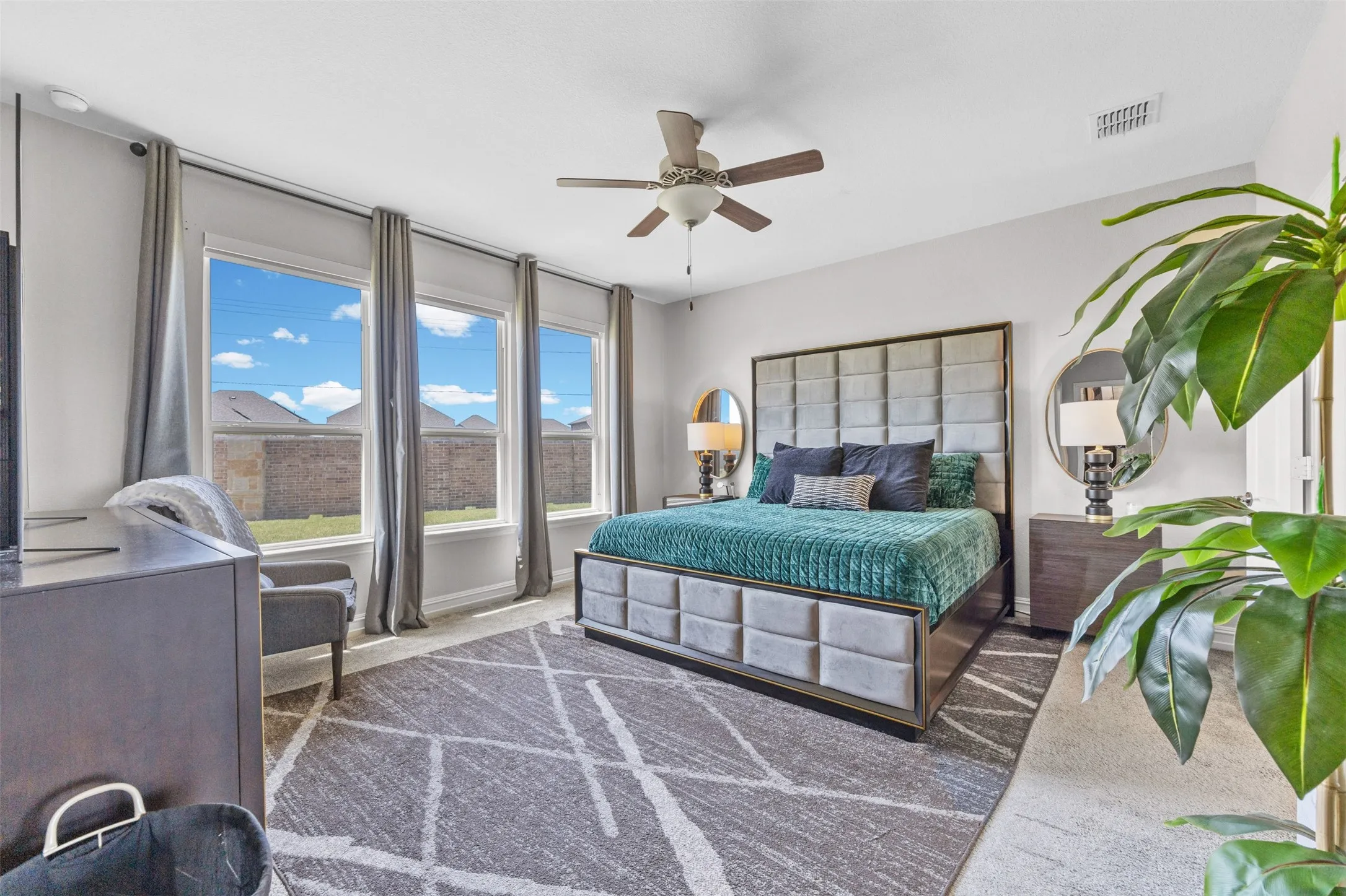 Spacious room featuring multiple large windows, soft carpet flooring, and a ceiling fan