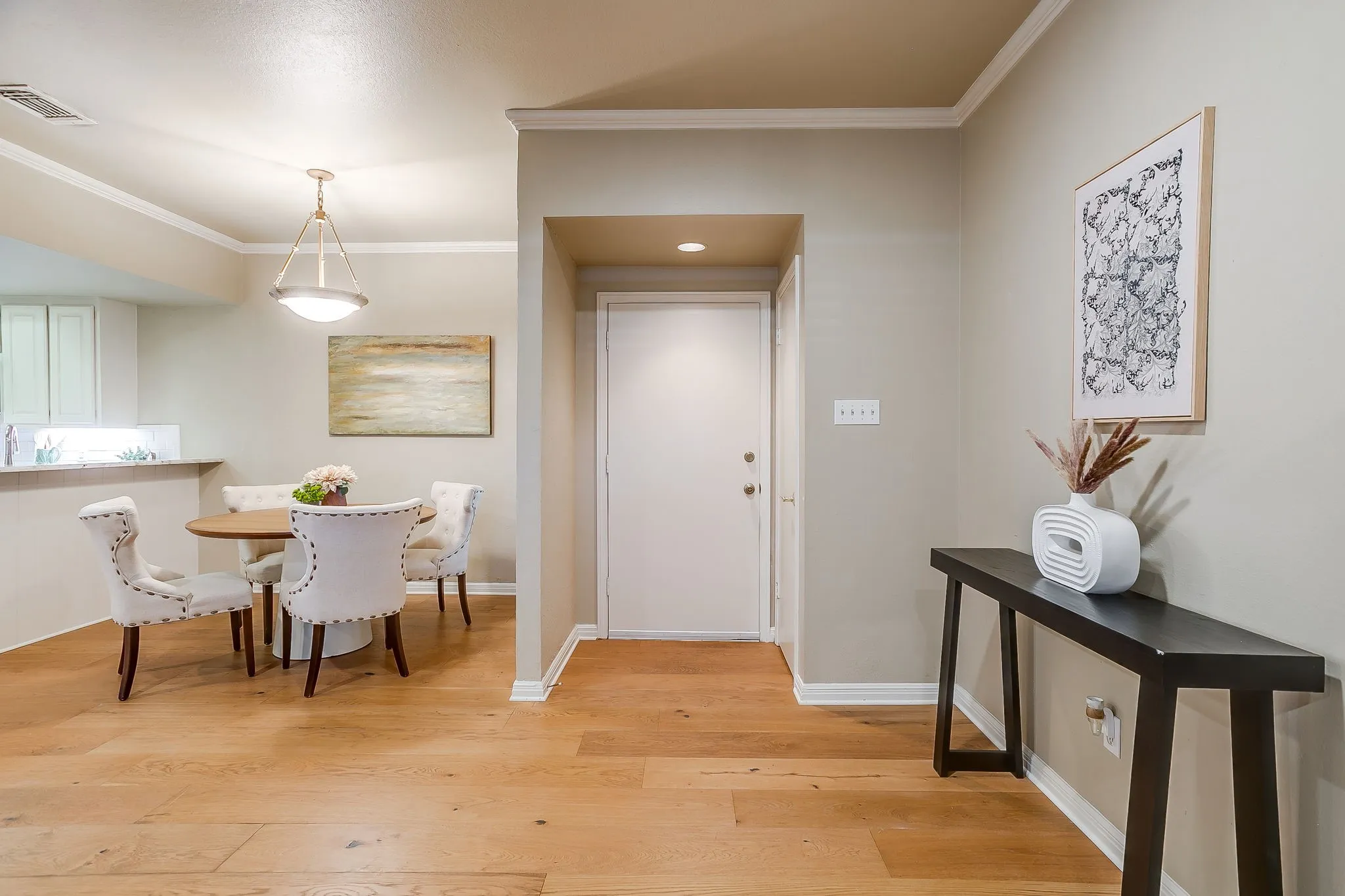 Foyer area showcasing wood-finish flooring, neutral wall tones, and crown molding