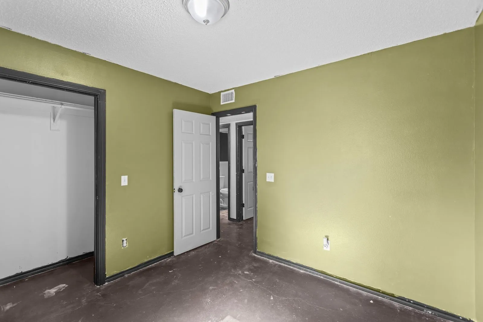 Room featuring a flush-mount ceiling light fixture, textured walls, and a closet with shelving