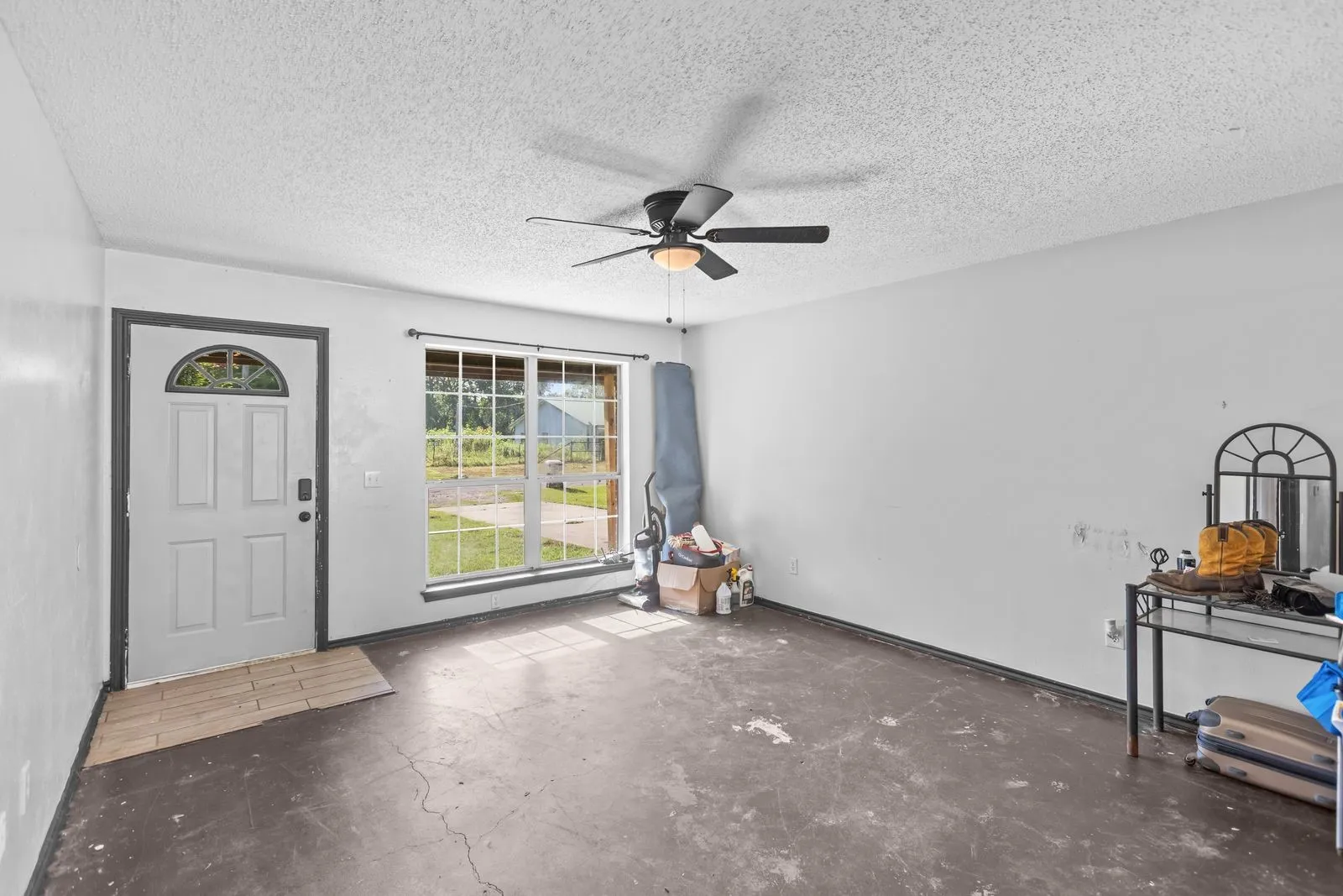 Living area featuring a window with exterior views, a ceiling fan, and a front entry door with an arched glass insert