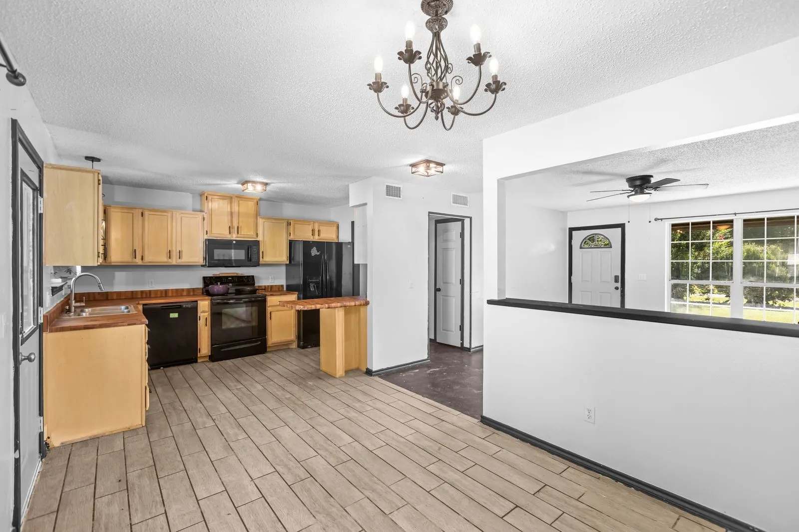 Kitchen featuring wood-finish cabinetry, black appliances, a double basin sink, and wood-look countertops