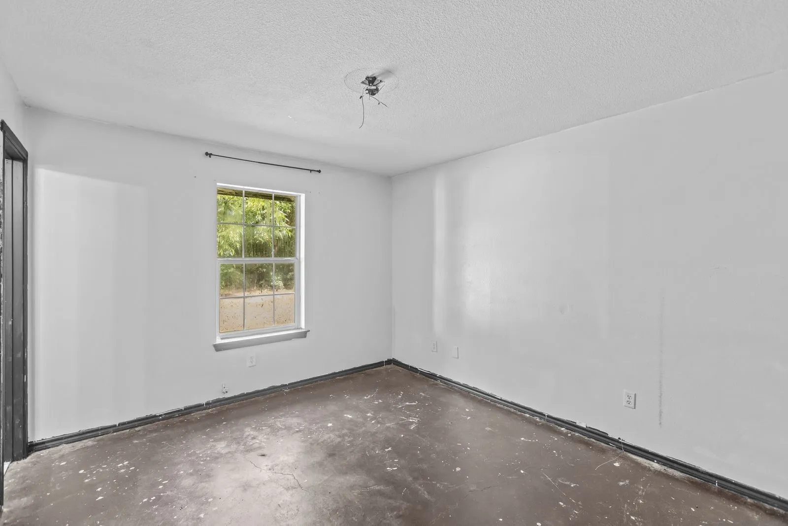 Windowed room featuring painted white walls and a concrete floor