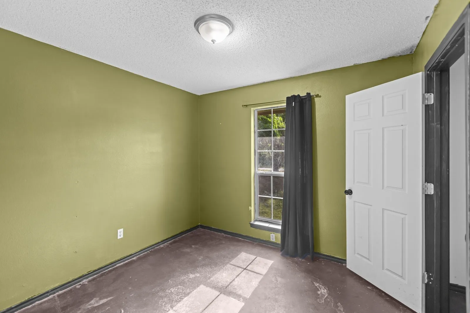 Room featuring a window with natural light, a ceiling-mounted light fixture, and a paneled interior door