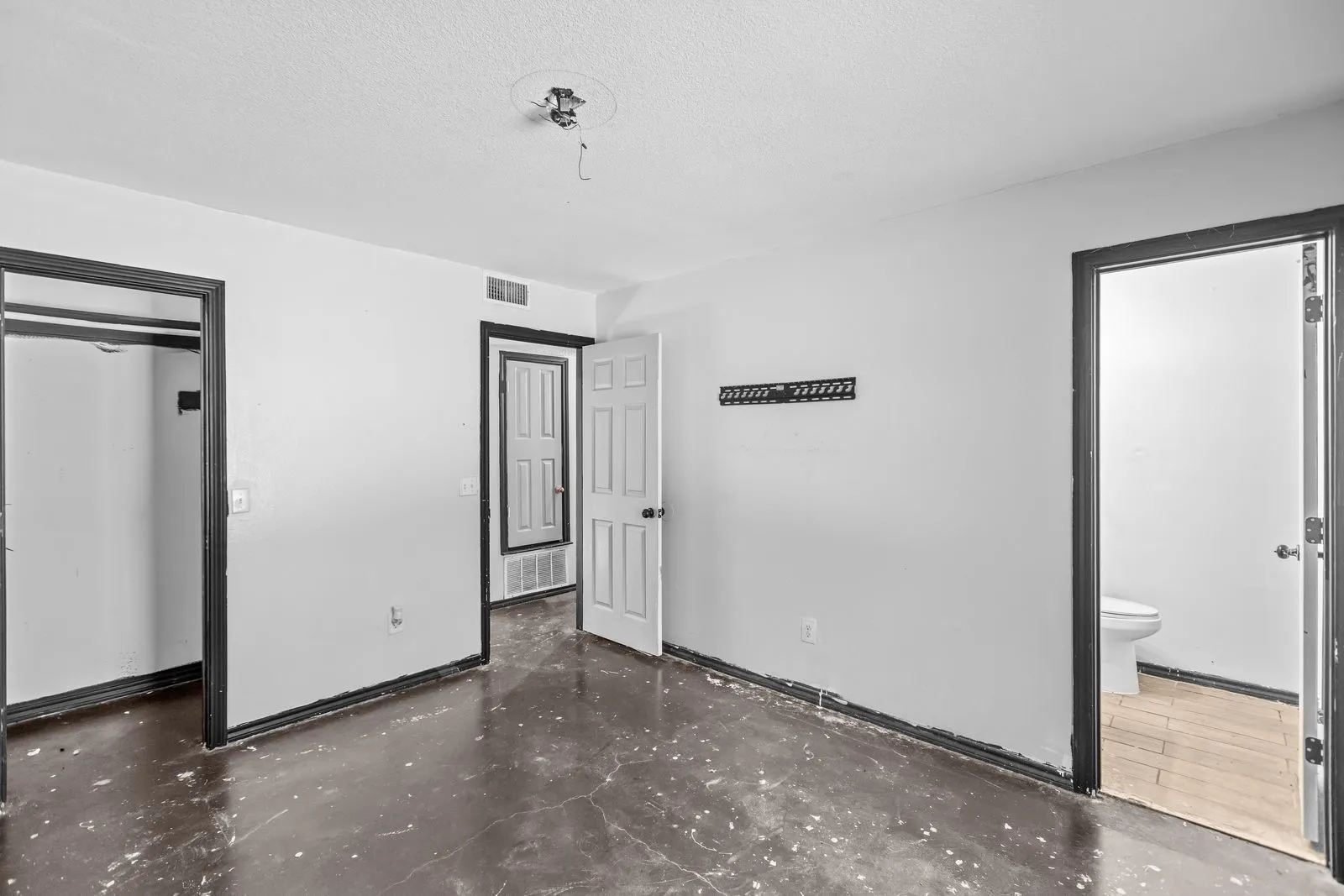 Interior space with dark-trimmed doorways, a closet opening, and a visible toilet in an adjacent room
