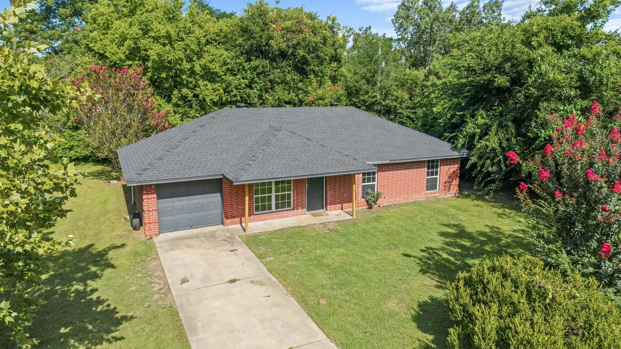 Brick exterior with a dark shingle roof and an attached garage