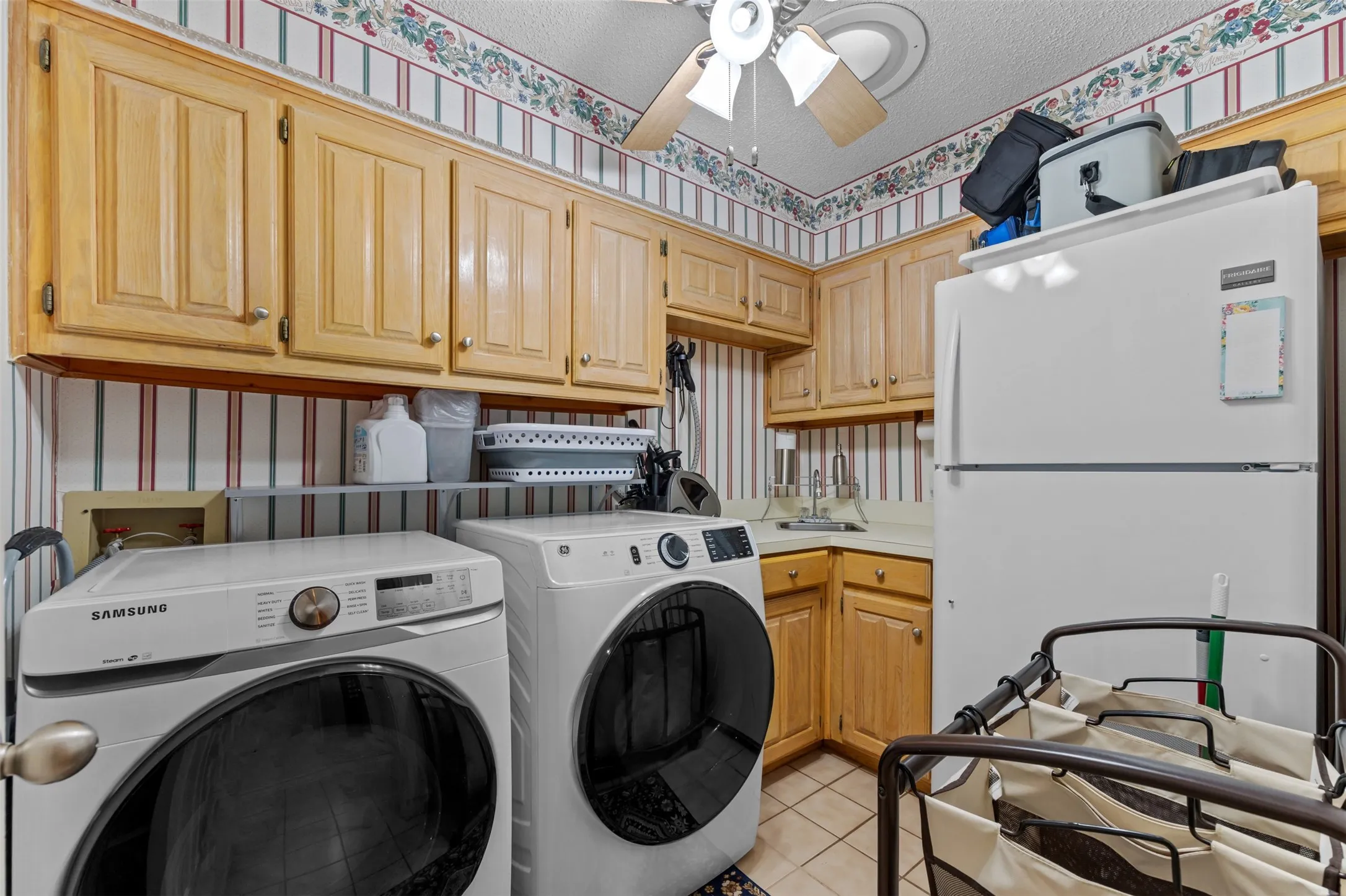 Utility room featuring wood cabinetry, a utility sink, and tile flooring