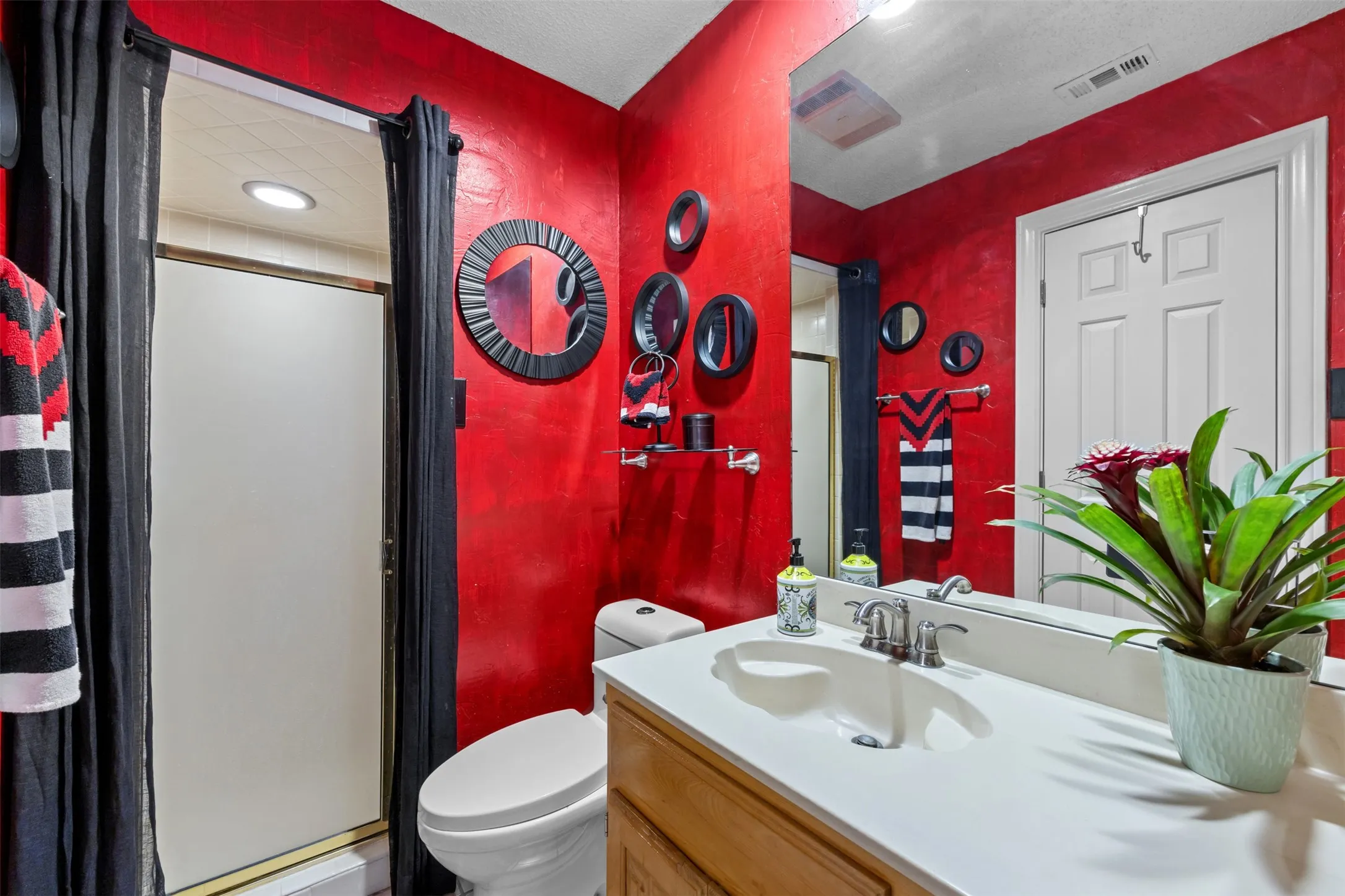 Bathroom featuring a single vanity with a white countertop and chrome faucet, a standard toilet, and a shower with frosted glass doors
