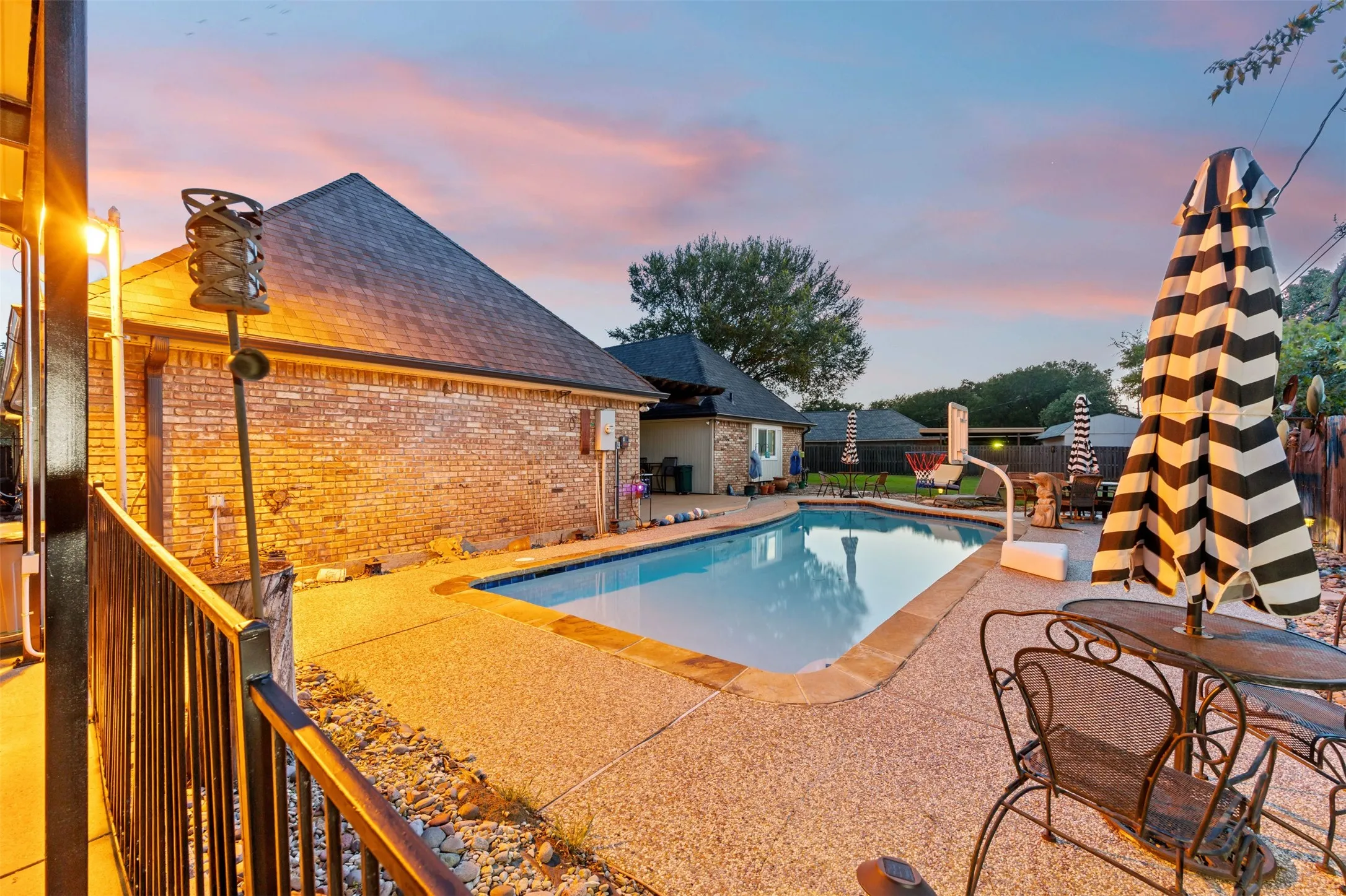 In-ground swimming pool with an expansive aggregate concrete deck, surrounded by brick exterior architecture