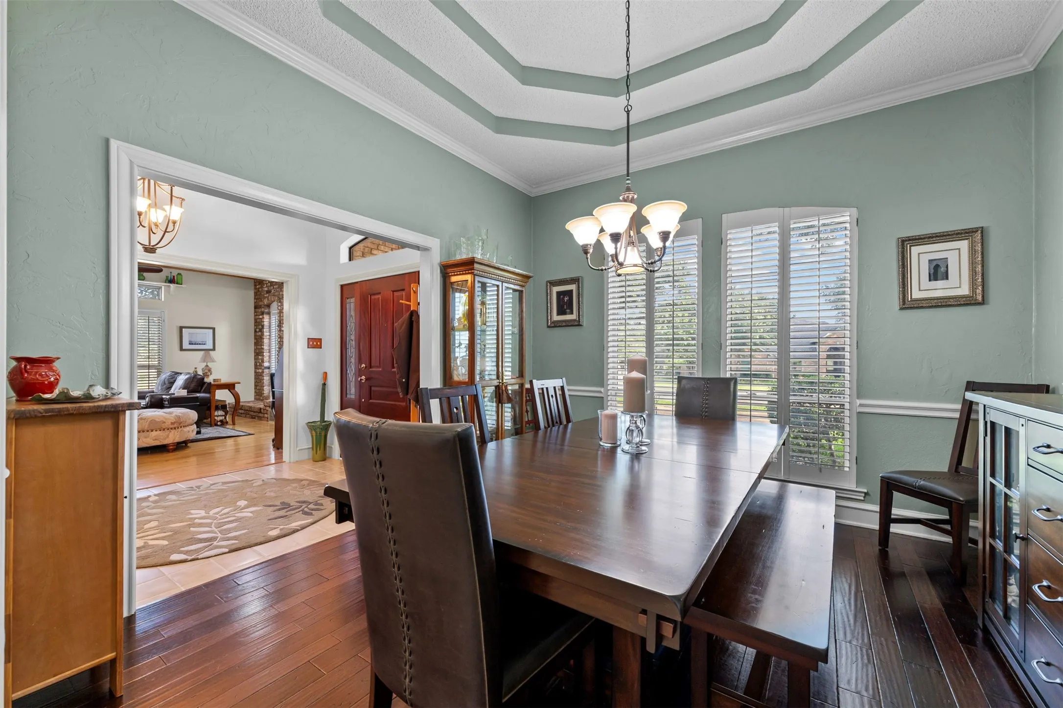 Dining area featuring wood-finish flooring, a tray ceiling, and a chandelier