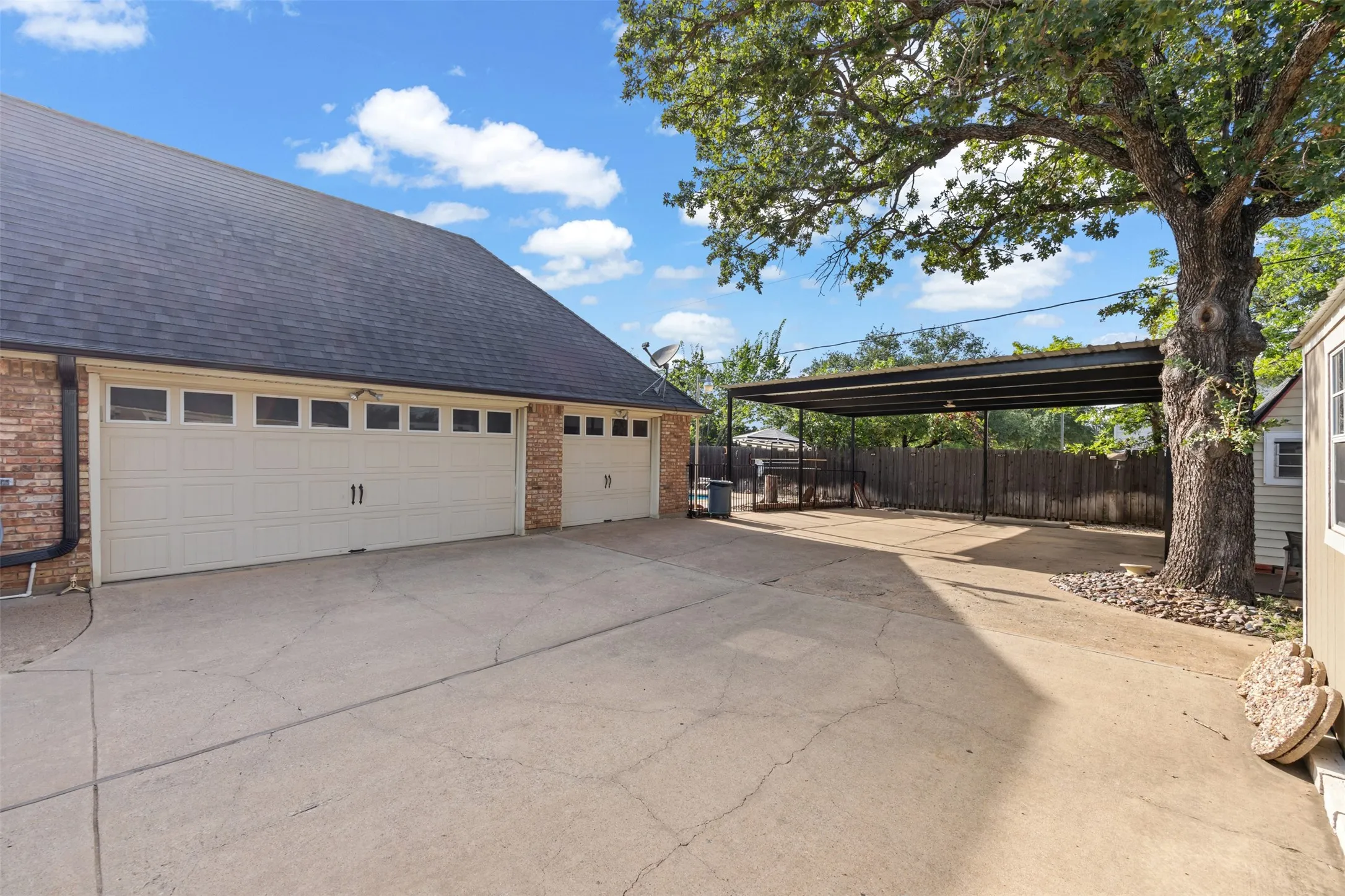 Expansive concrete driveway servicing a two-car garage and an additional single-car garage with paneling and window inserts