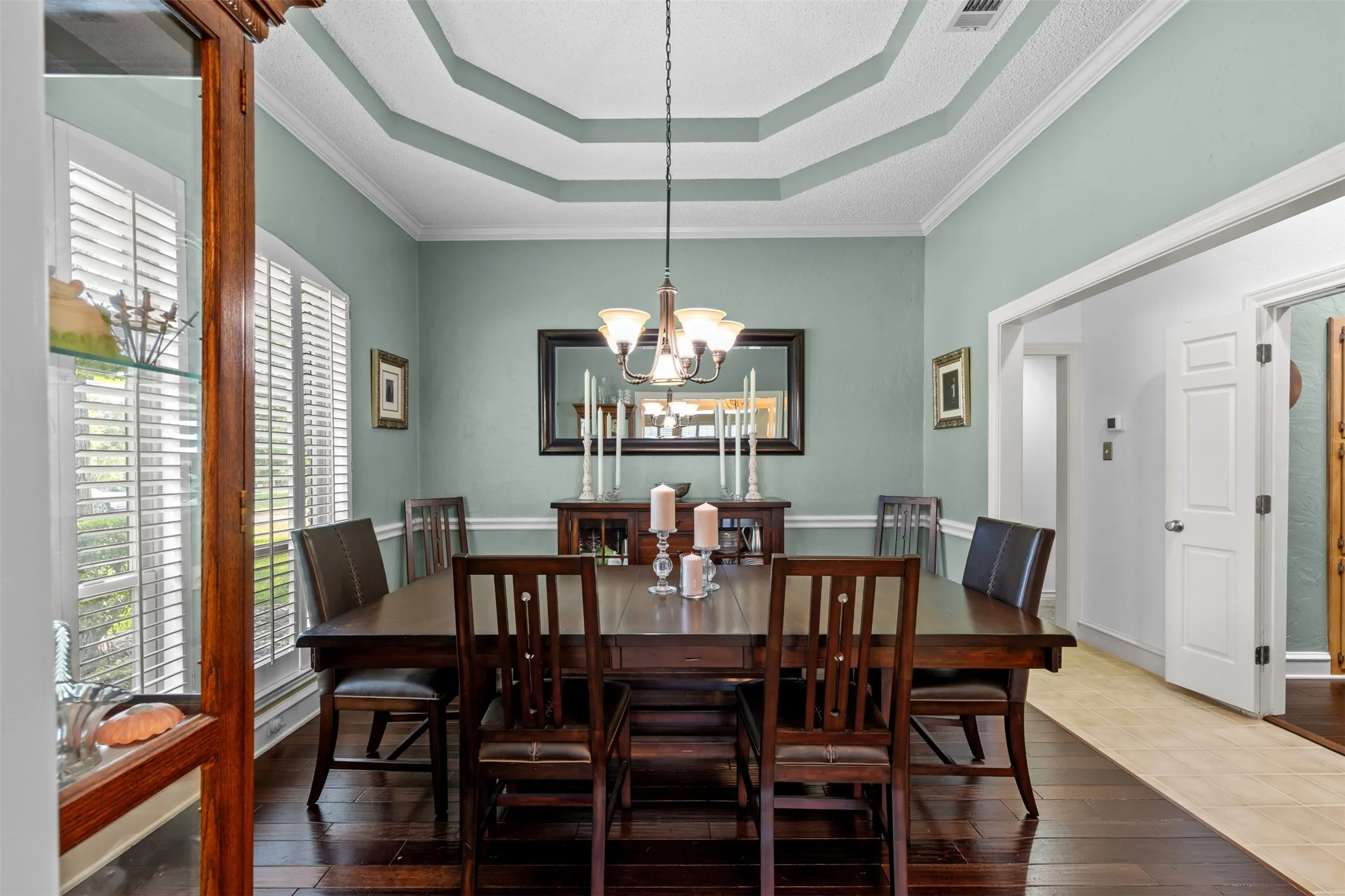 Formal dining space featuring a tray ceiling, crown molding, and wood-finish flooring