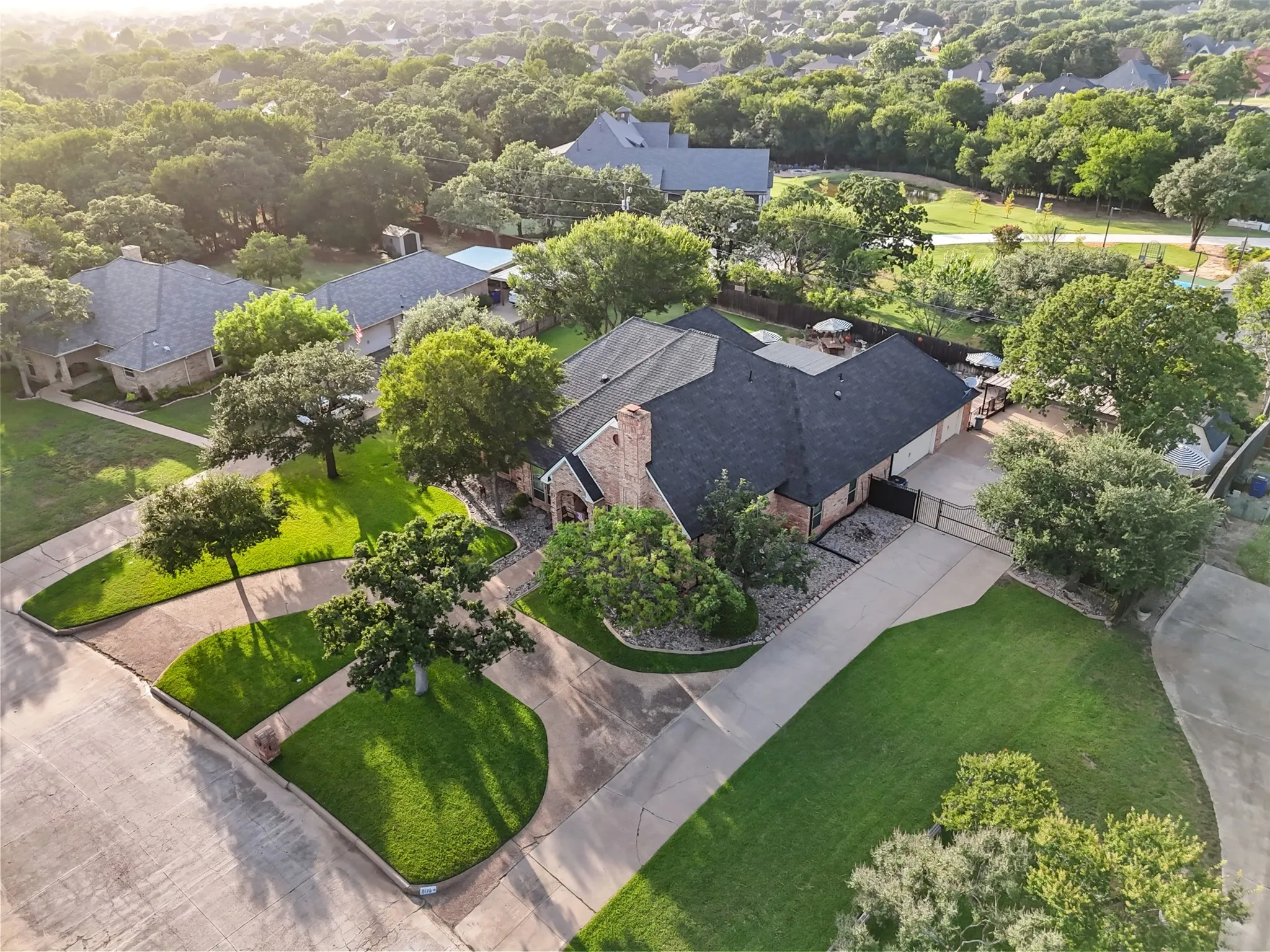Brick exterior residence with a dark shingle roof and a spacious paved driveway