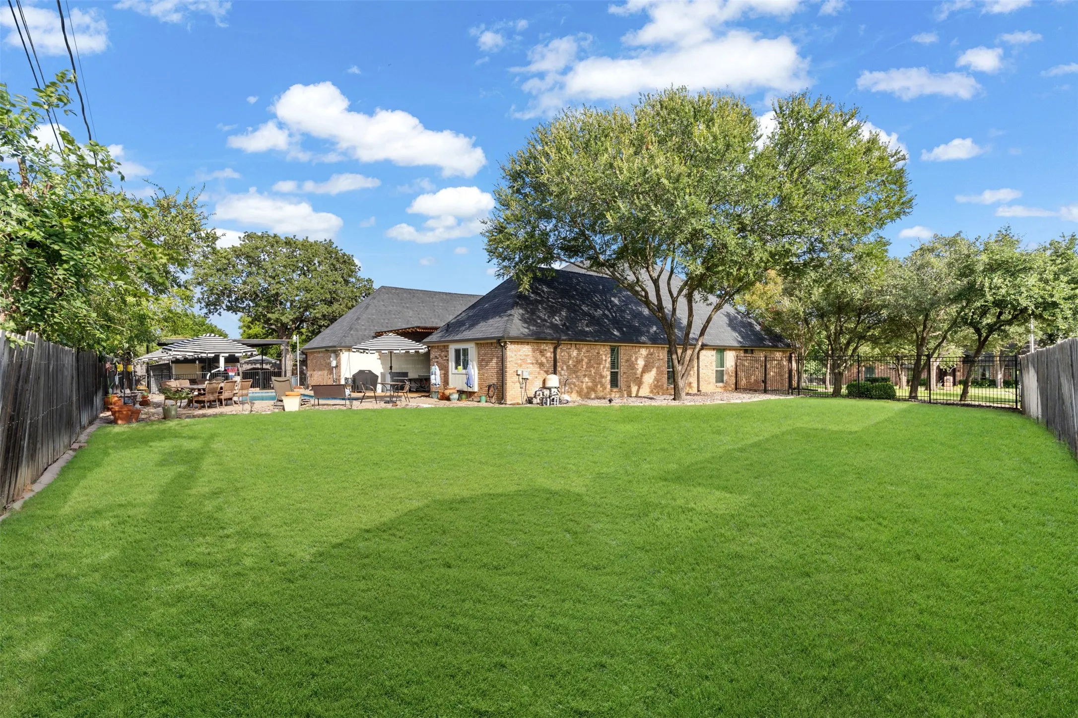 Expansive backyard featuring a lush green lawn, mature trees, and a privacy fence