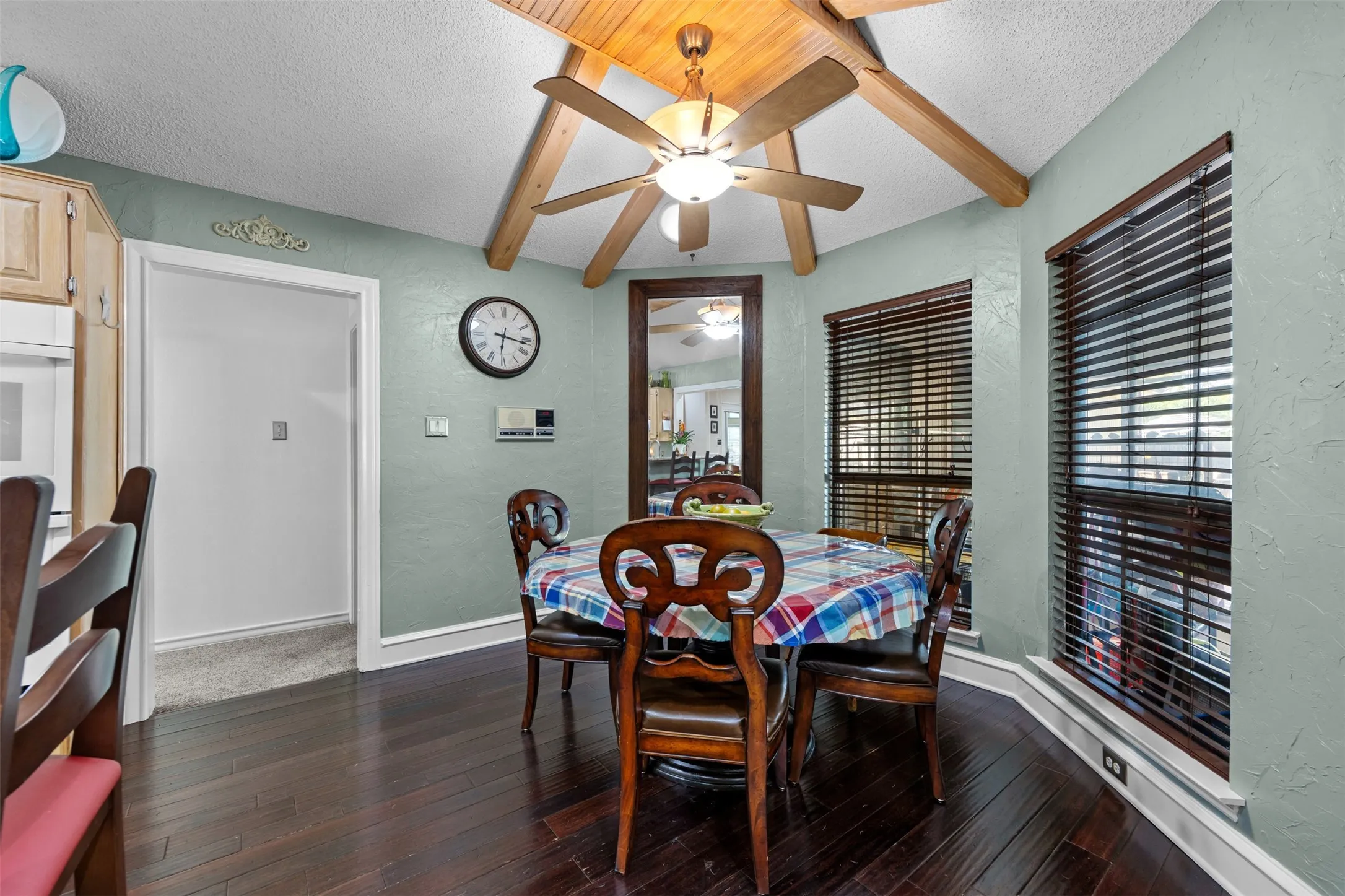 Dining area featuring wood-finish flooring, a ceiling fan with light fixture, and two windows with blinds