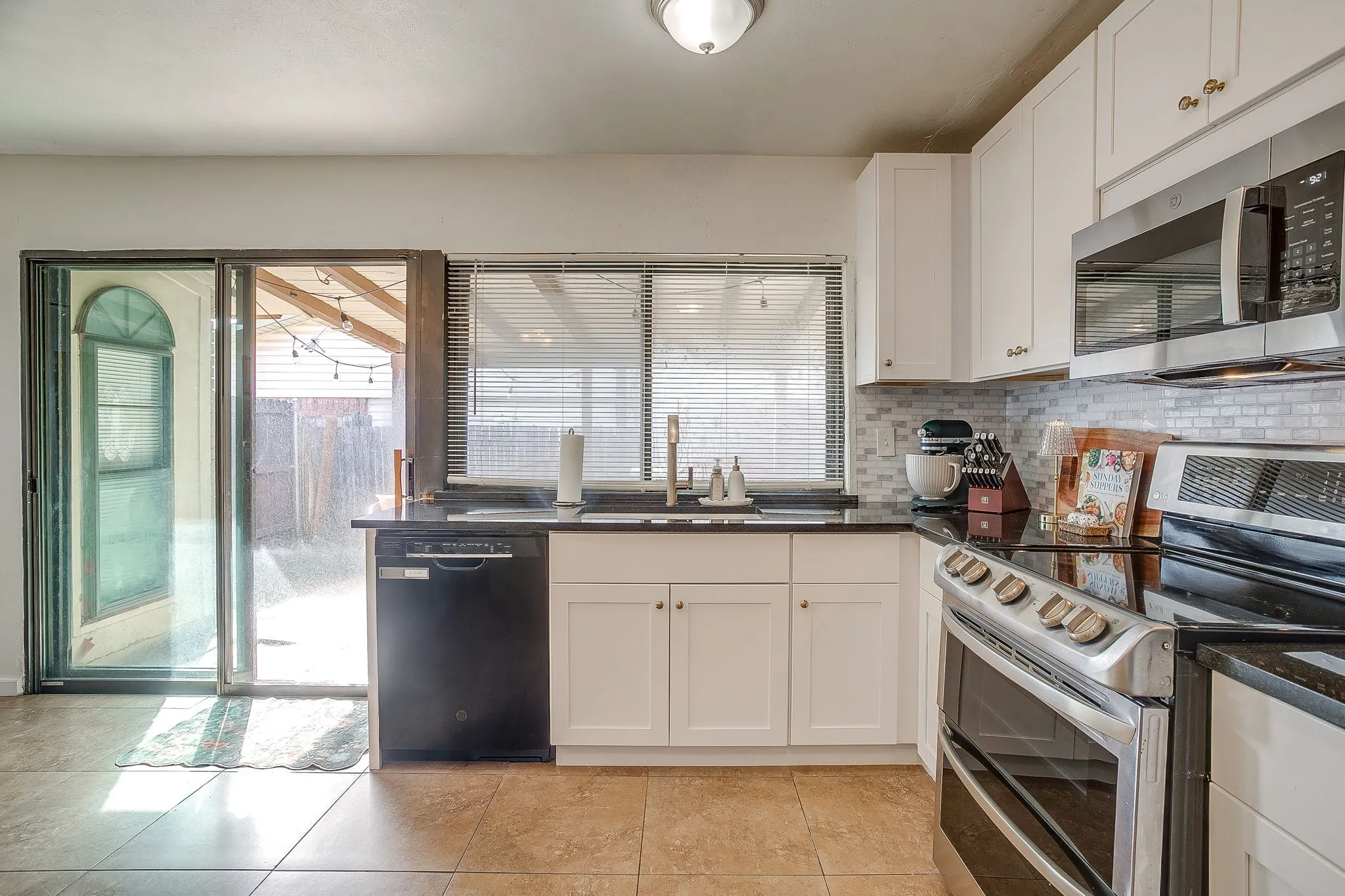 Great natural light in this updated kitchen with granite counters, light and bright tiled backsplash and stainless appliances.