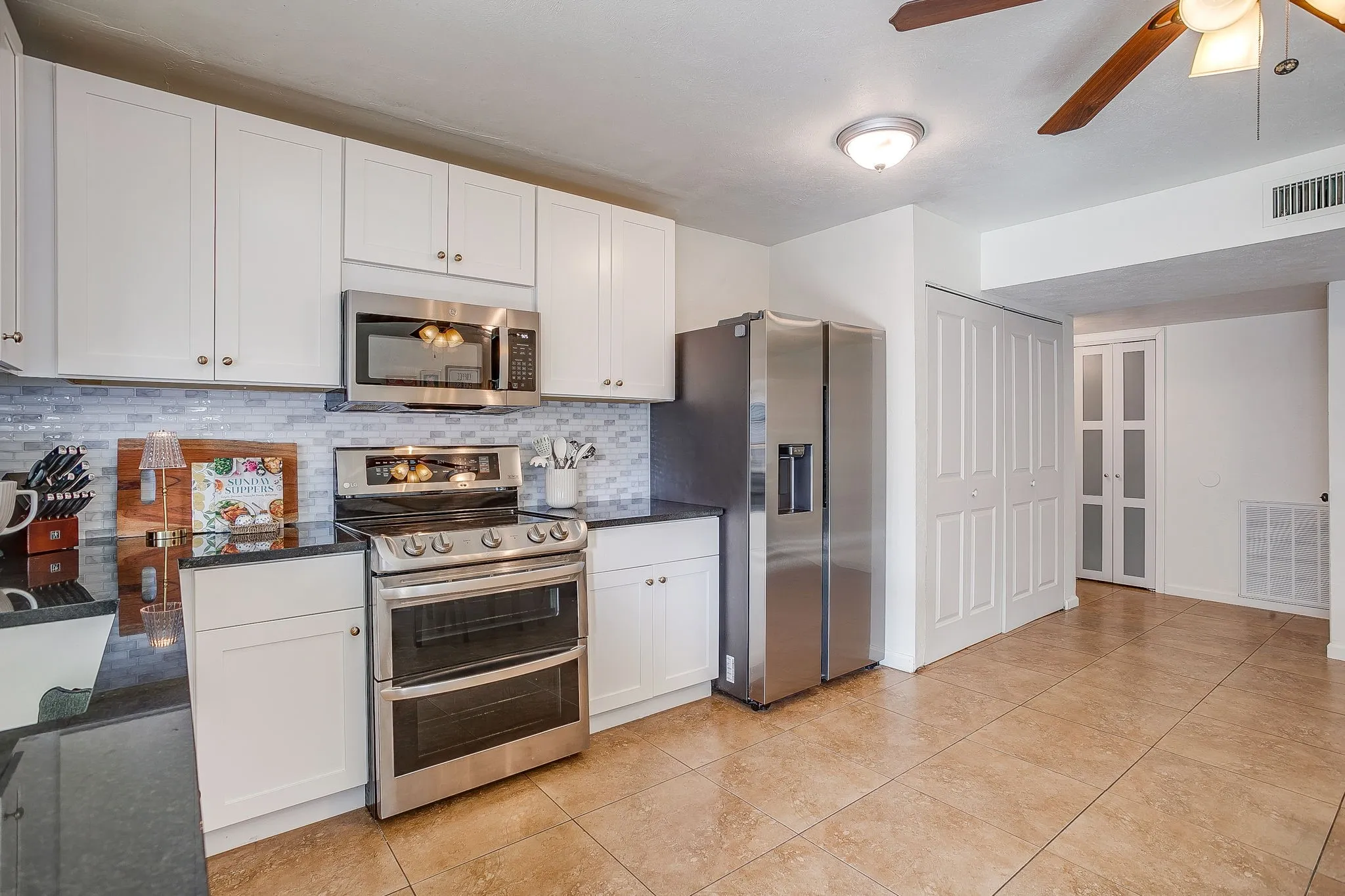 Updated kitchen space with granite counters, oversized single basin sink, stainless appliances, tiled backsplash.