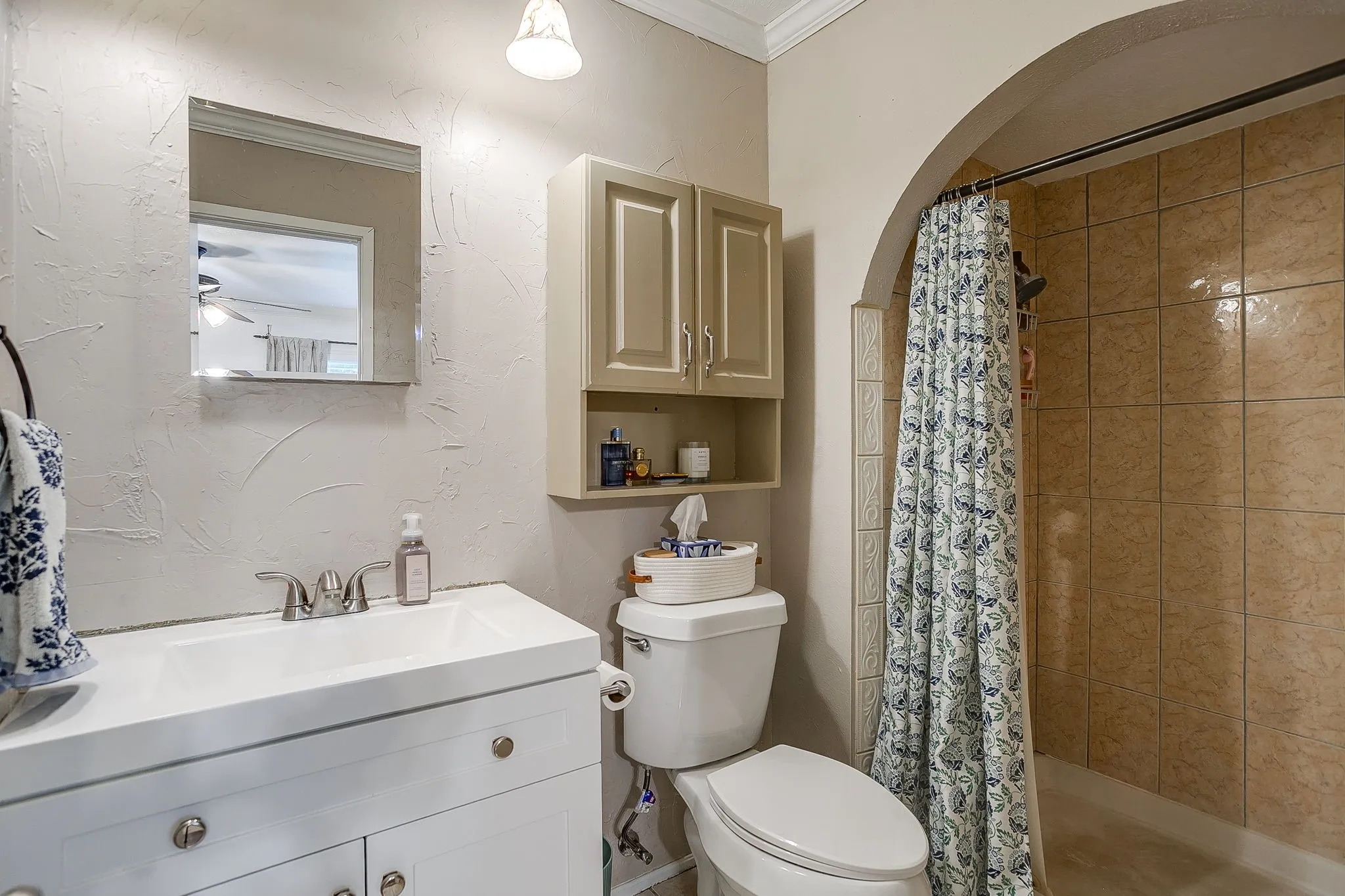 Primary bath with arched entry tiled shower, mounted cabinet and medicine cabinet, custom vanity.