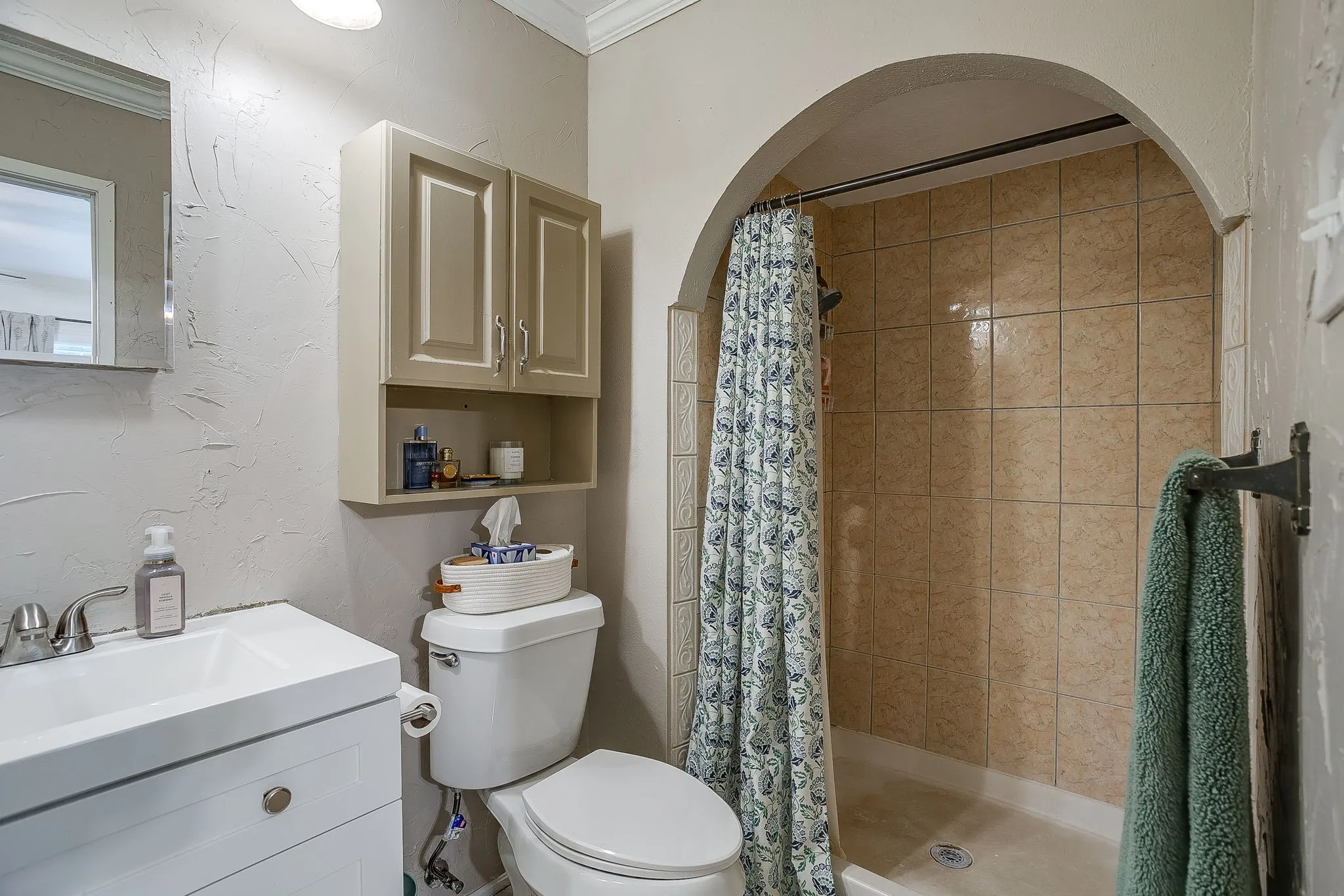 Primary bath with neutral paint, custom vanity, cabinet for extra storage, and beautiful tiled shower.