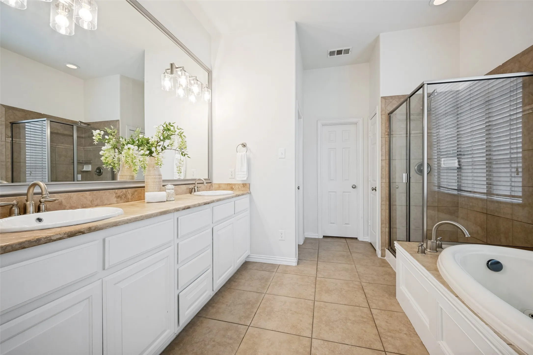 Master bathroom with double vanity, travertine stone countertops and a large soaking tub