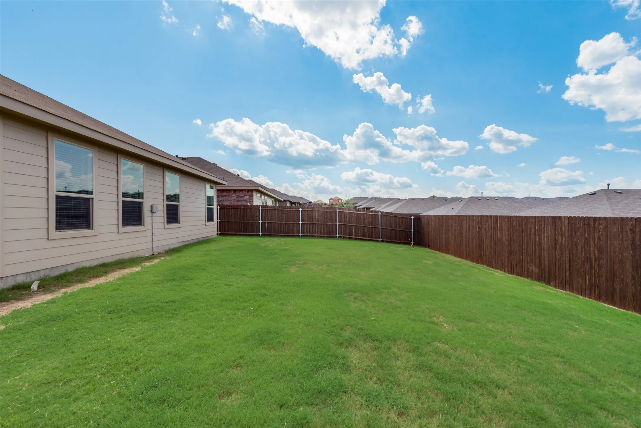 Expansive green lawn with a privacy fence