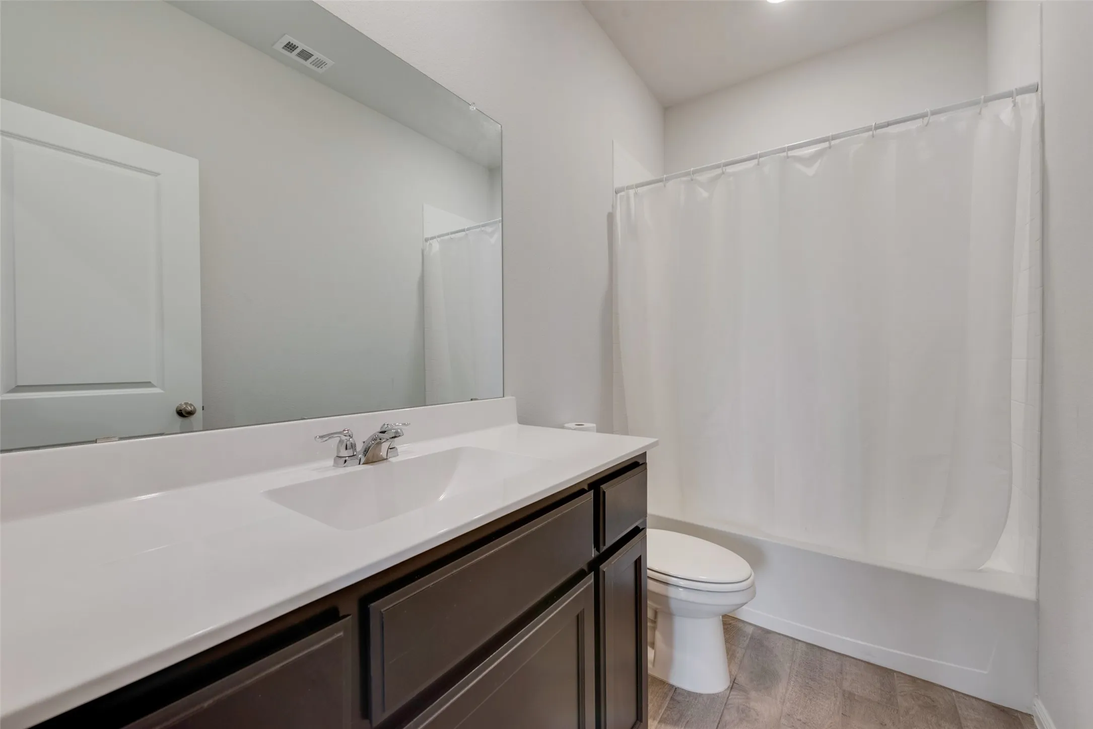 Bathroom featuring a dark wood-finish vanity with a white countertop, an integrated rectangular sink, and a chrome faucet