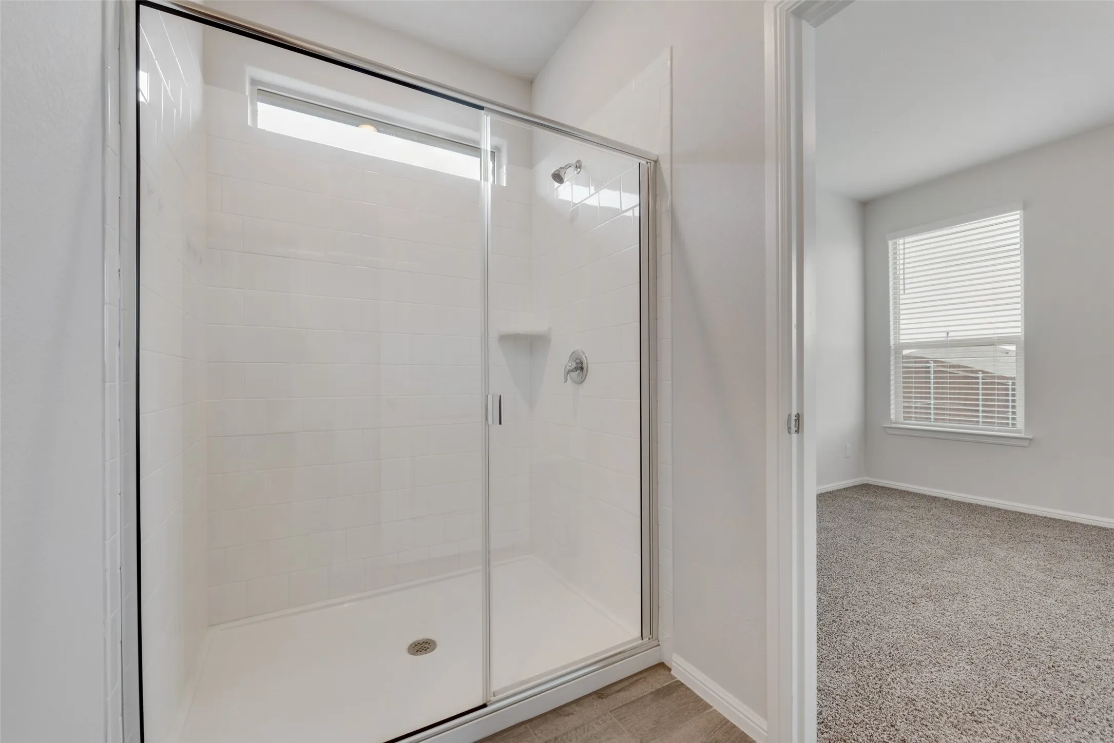 Glass-enclosed shower with subway tile surround, integrated shelving, and a transom window