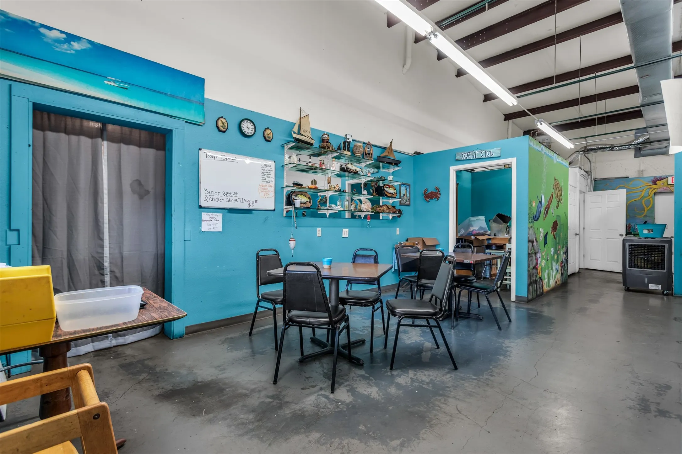 Open-concept commercial space featuring concrete flooring, exposed ceiling beams, and fluorescent strip lighting