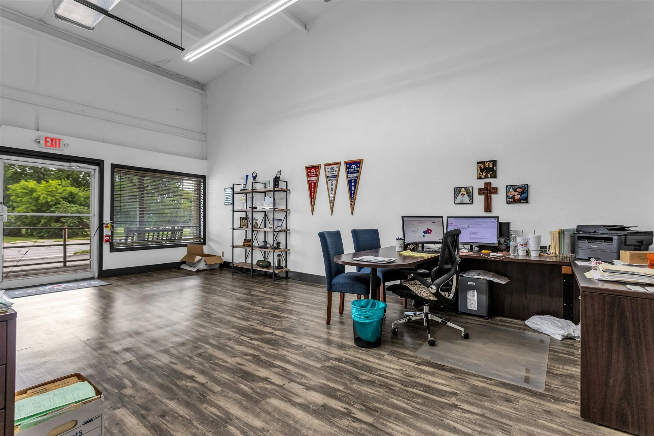 Open-concept commercial space featuring laminate flooring, high ceilings with fluorescent lighting