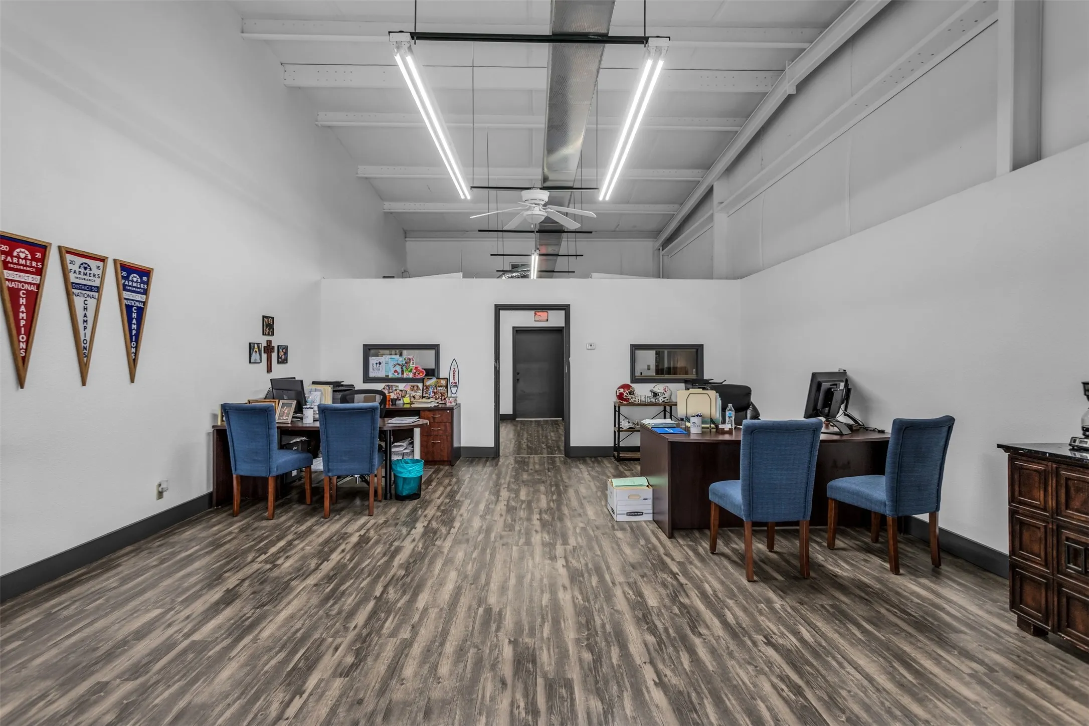 Spacious open-concept interior featuring laminate flooring, white walls, and an exposed ceiling with
lighting